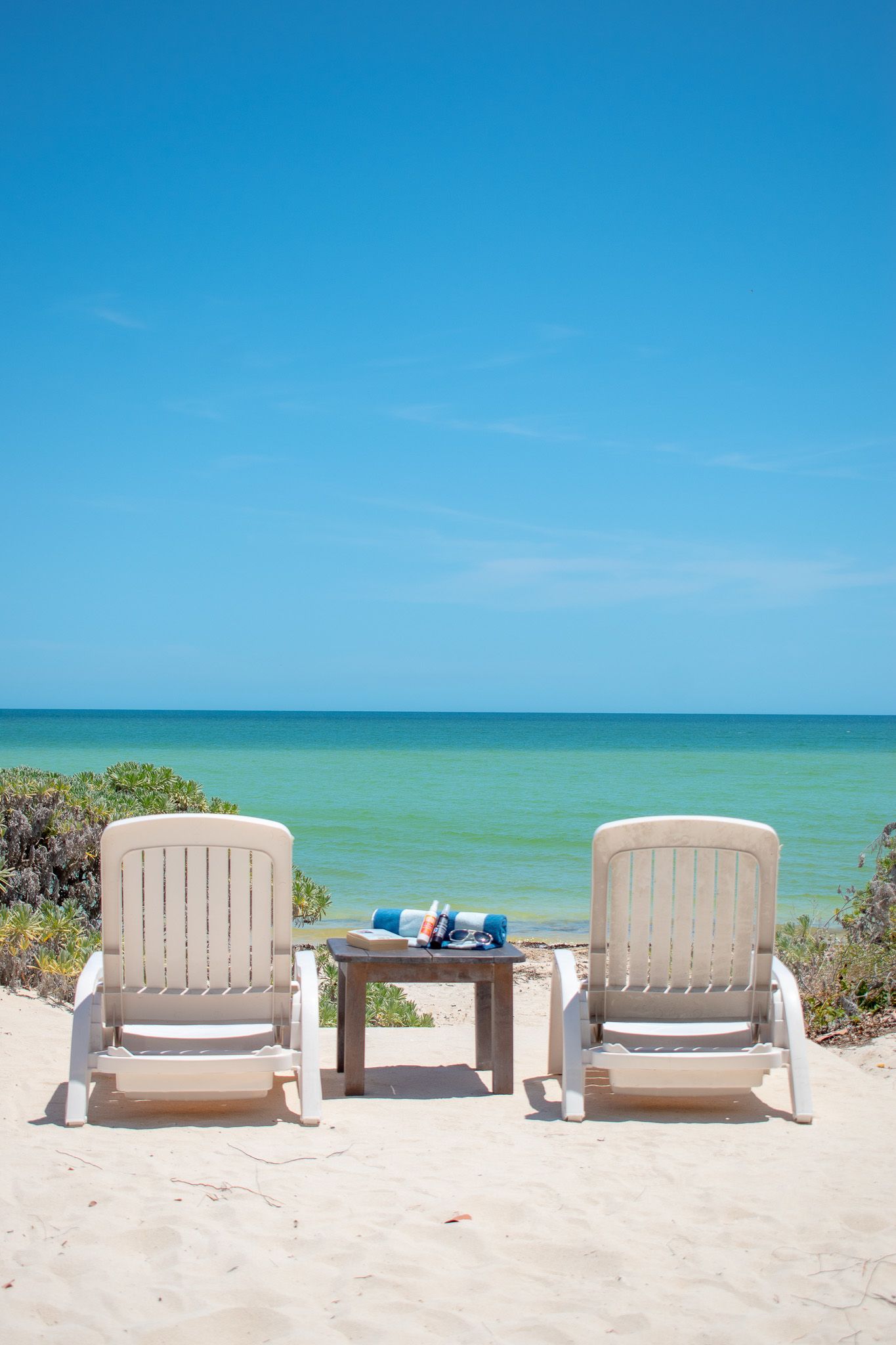 Dos sillas y una mesa en una playa con vista al mar en Tecnohotel Beach