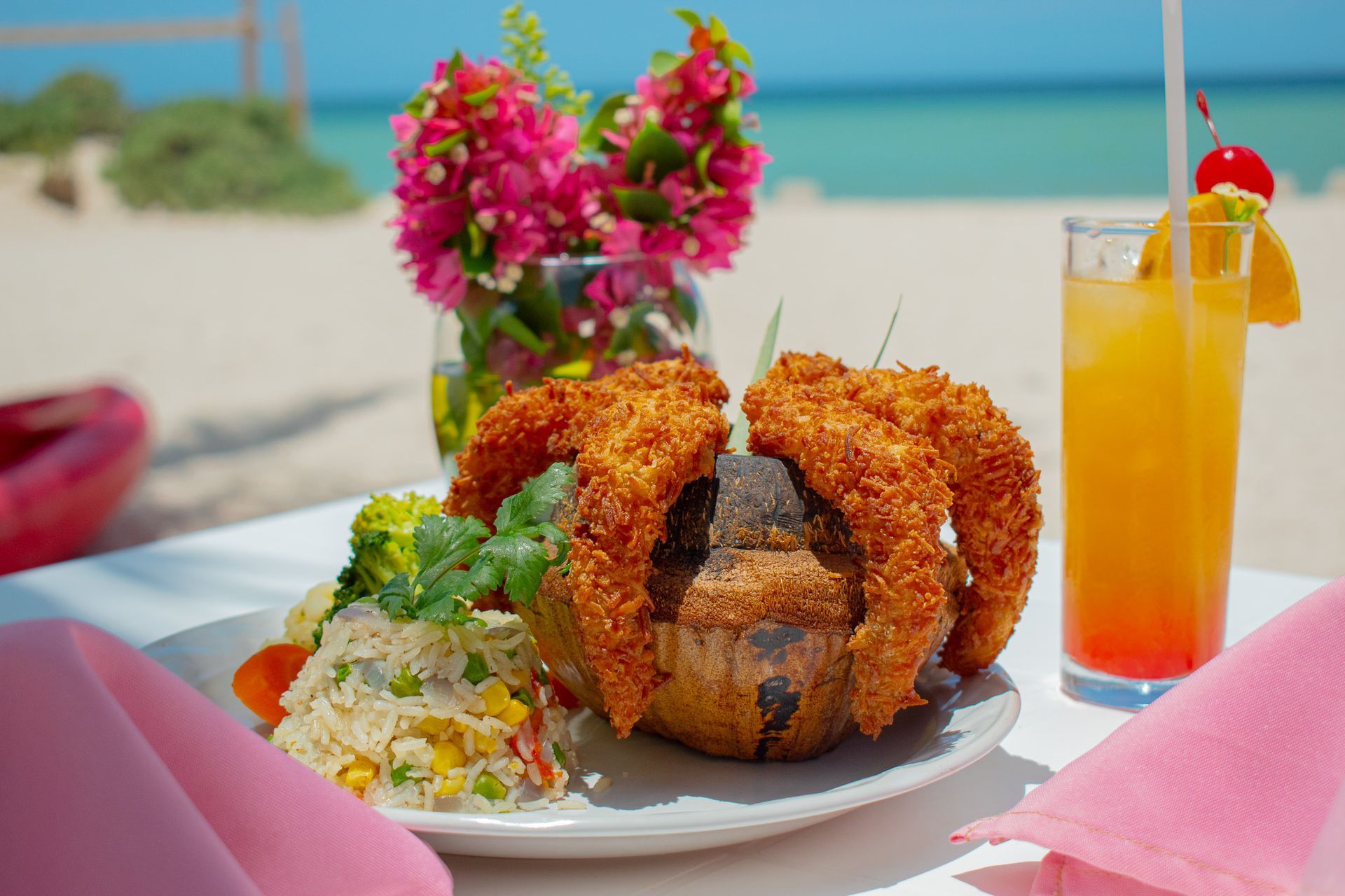 Un plato de comida y una bebida en una mesa en la playa Tecnohotel Beach