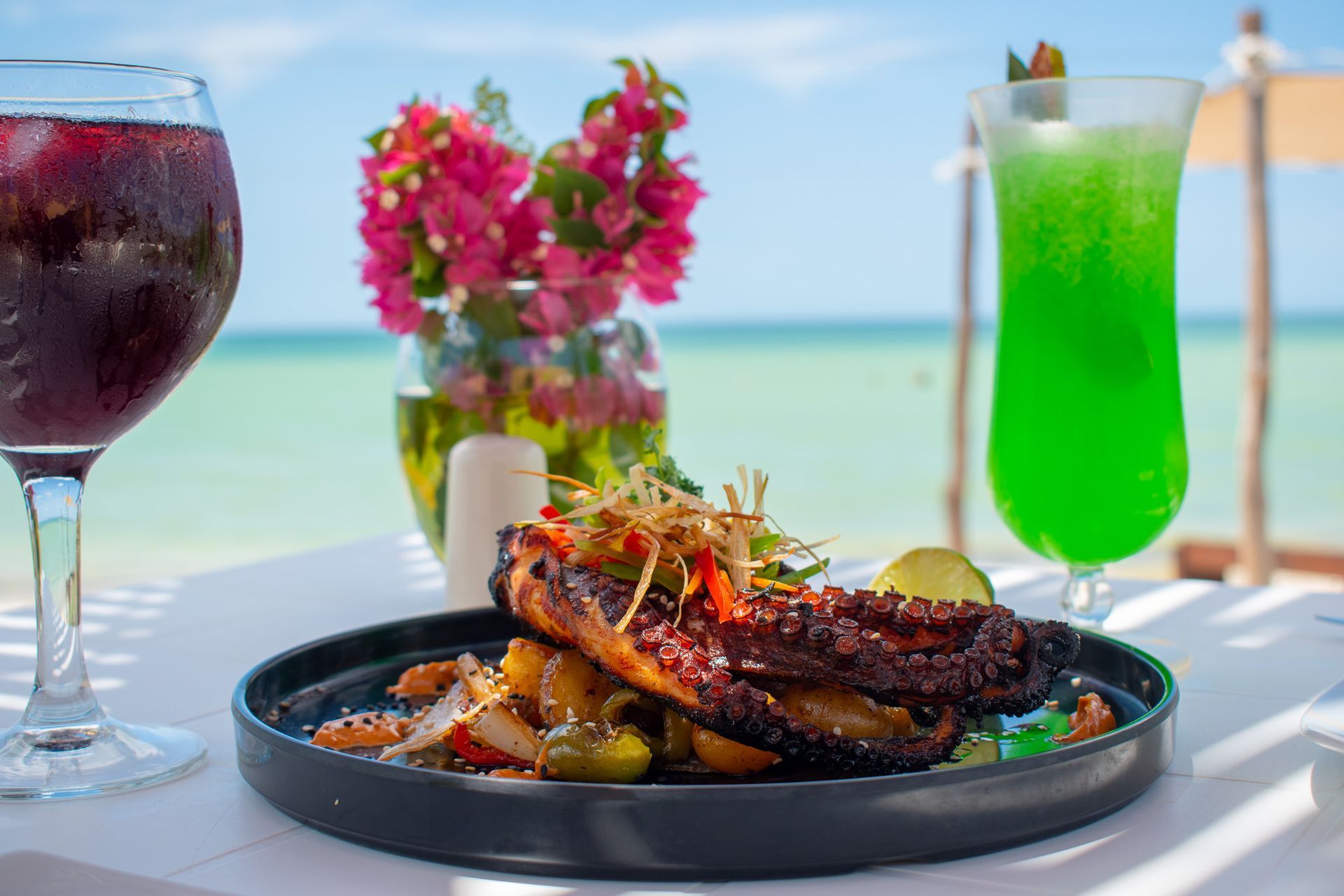 Un plato de comida y bebidas en una mesa con vista al mar en Tecnohotel Beach