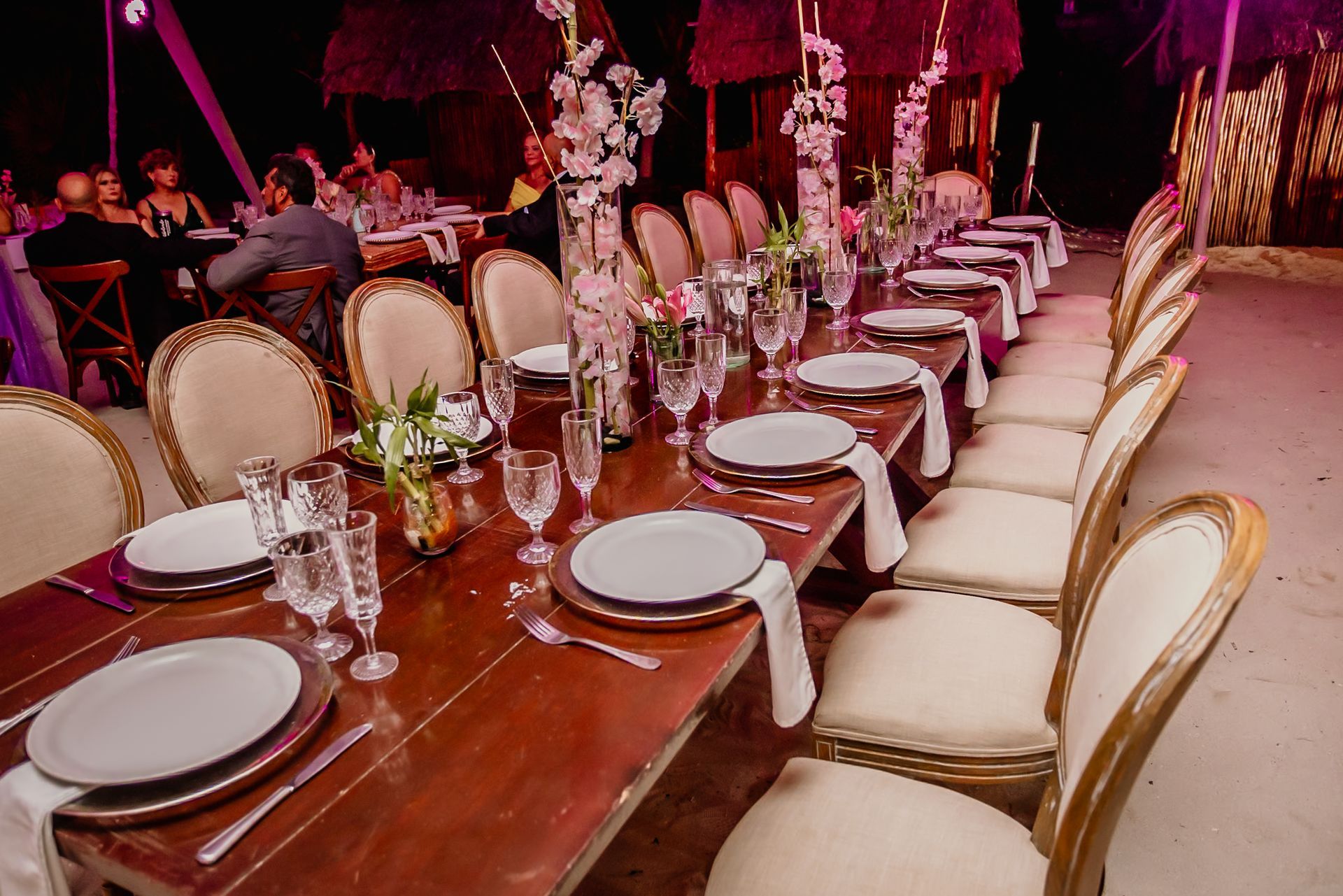 Una mesa larga de madera con platos, vasos y cubiertos sobre ella.