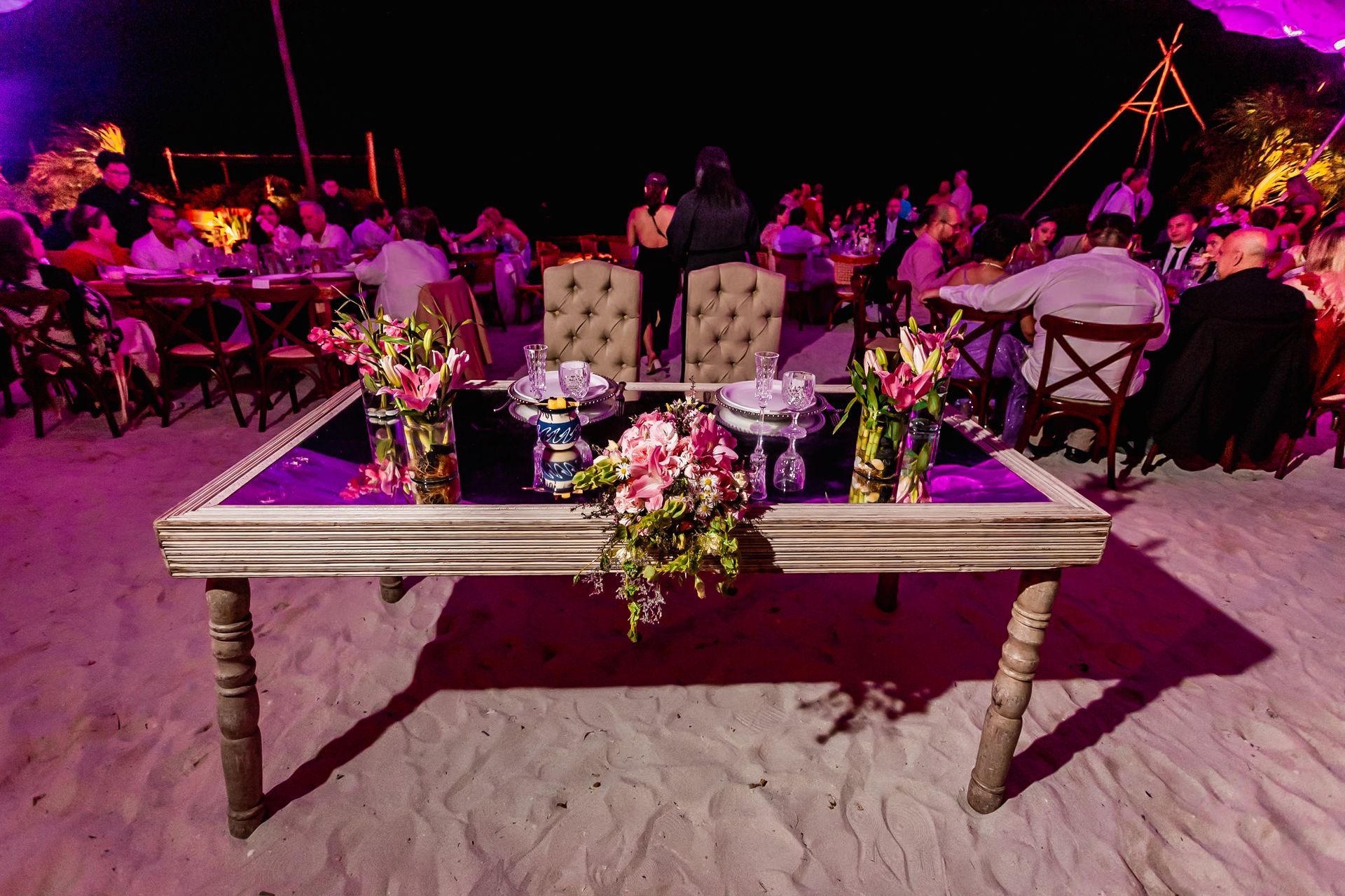 Una mesa de novios está preparada en la playa para la recepción de una boda.