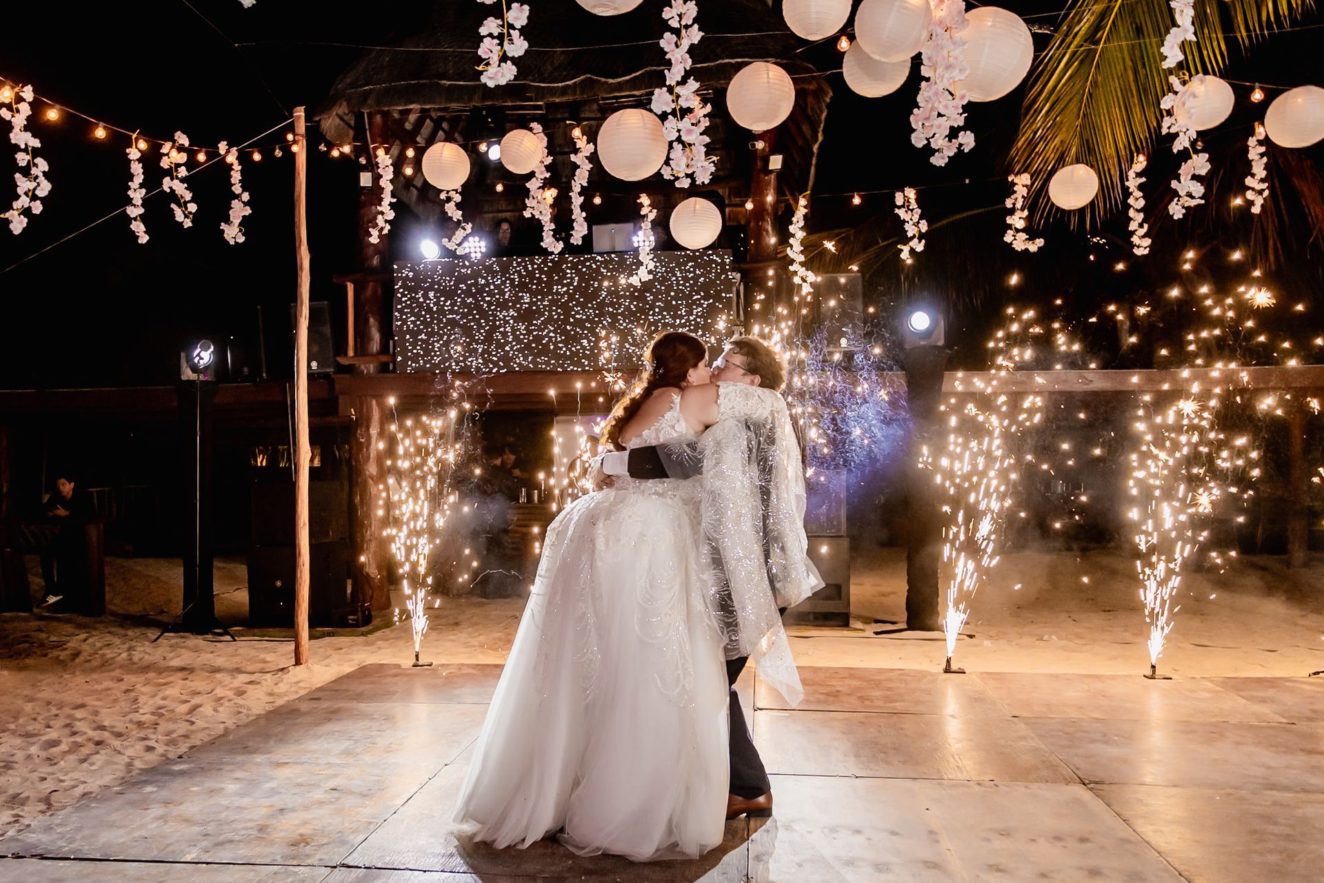 Una novia y un novio se besan en una pista de baile frente a los fuegos artificiales.