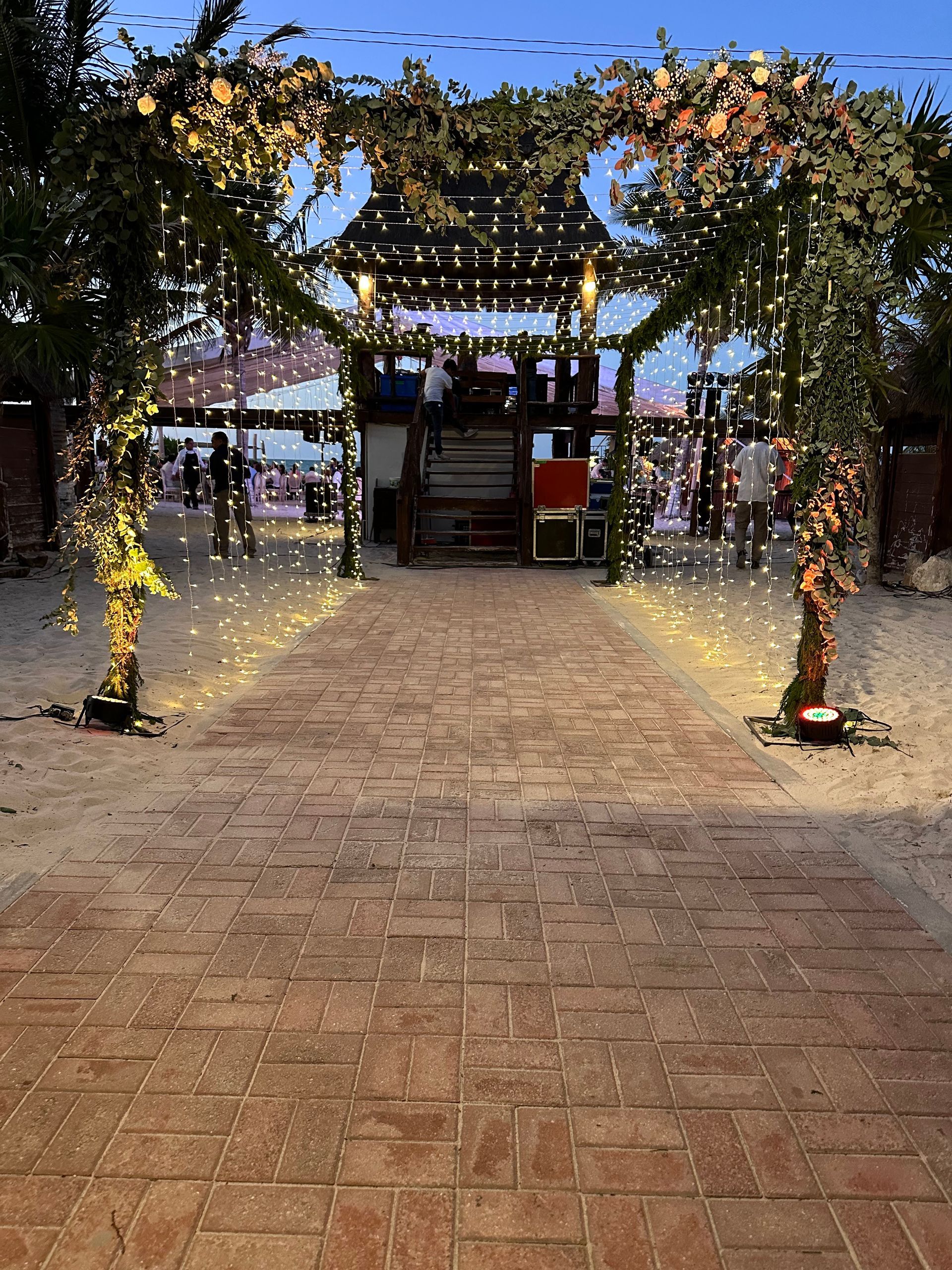 Una pasarela de ladrillos que conduce a un edificio decorado con luces y flores.