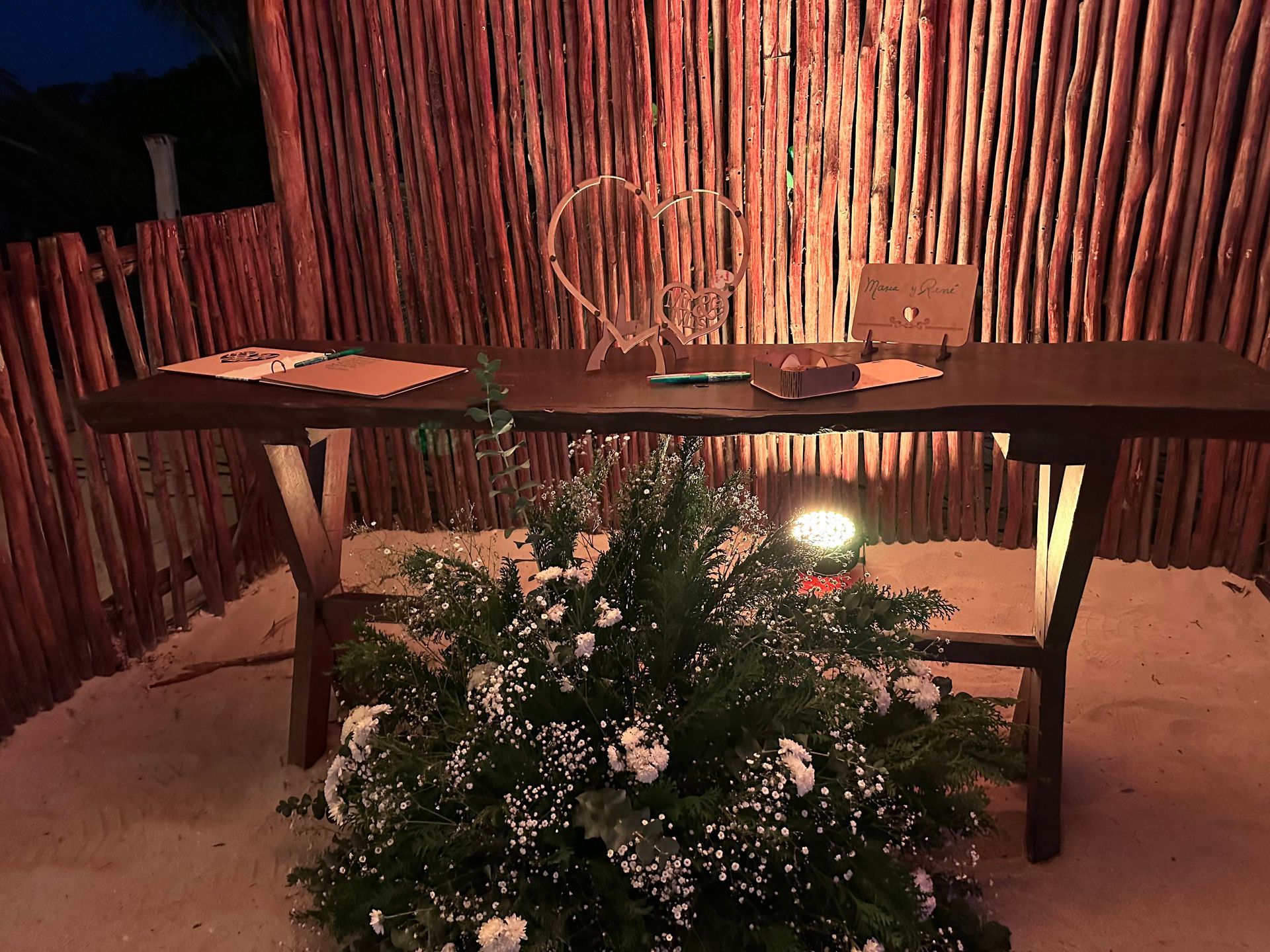 Una mesa de madera con un jarrón de flores delante de ella.