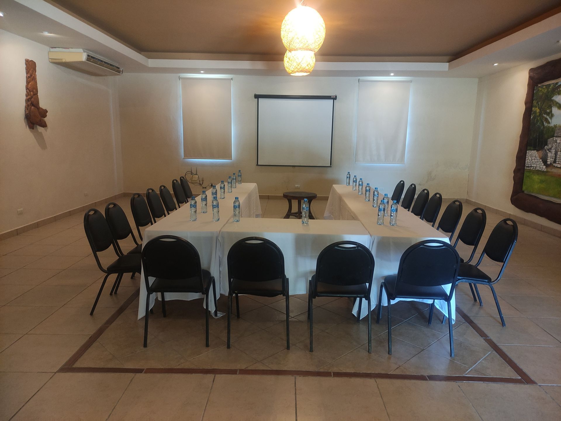 Una sala de conferencias con mesas y sillas y una pantalla de proyección en Tecnohotel Beach