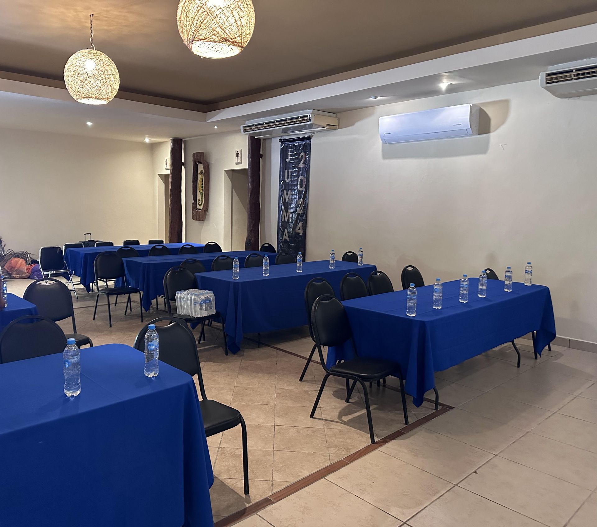 Una sala grande con mesas y sillas azules preparadas para una reunión en Tecnohotel Beach.