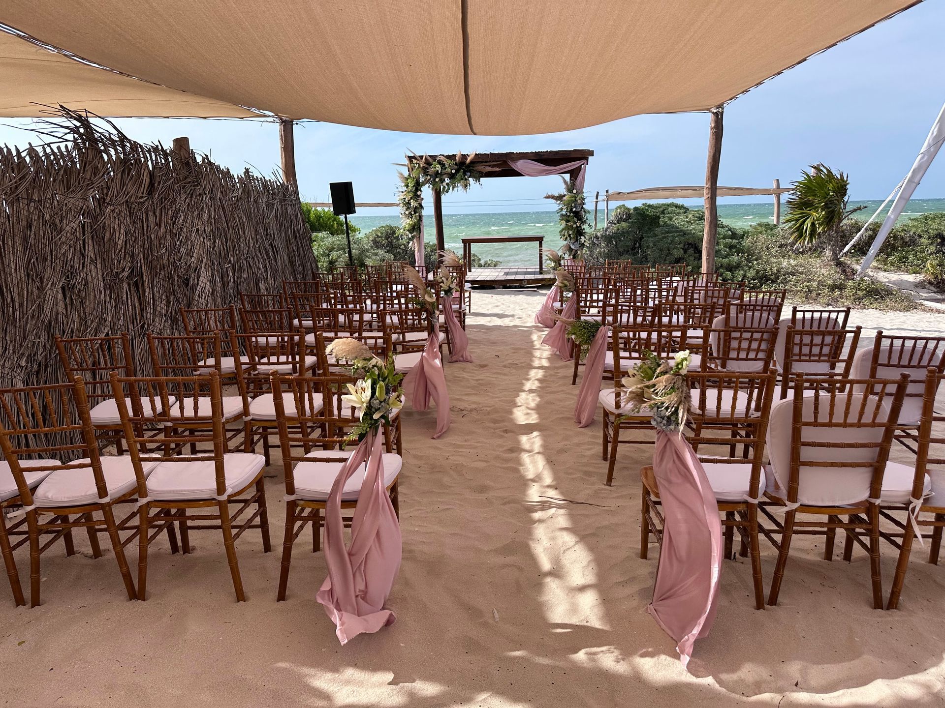 Se está celebrando una ceremonia de boda en la playa bajo un dosel.