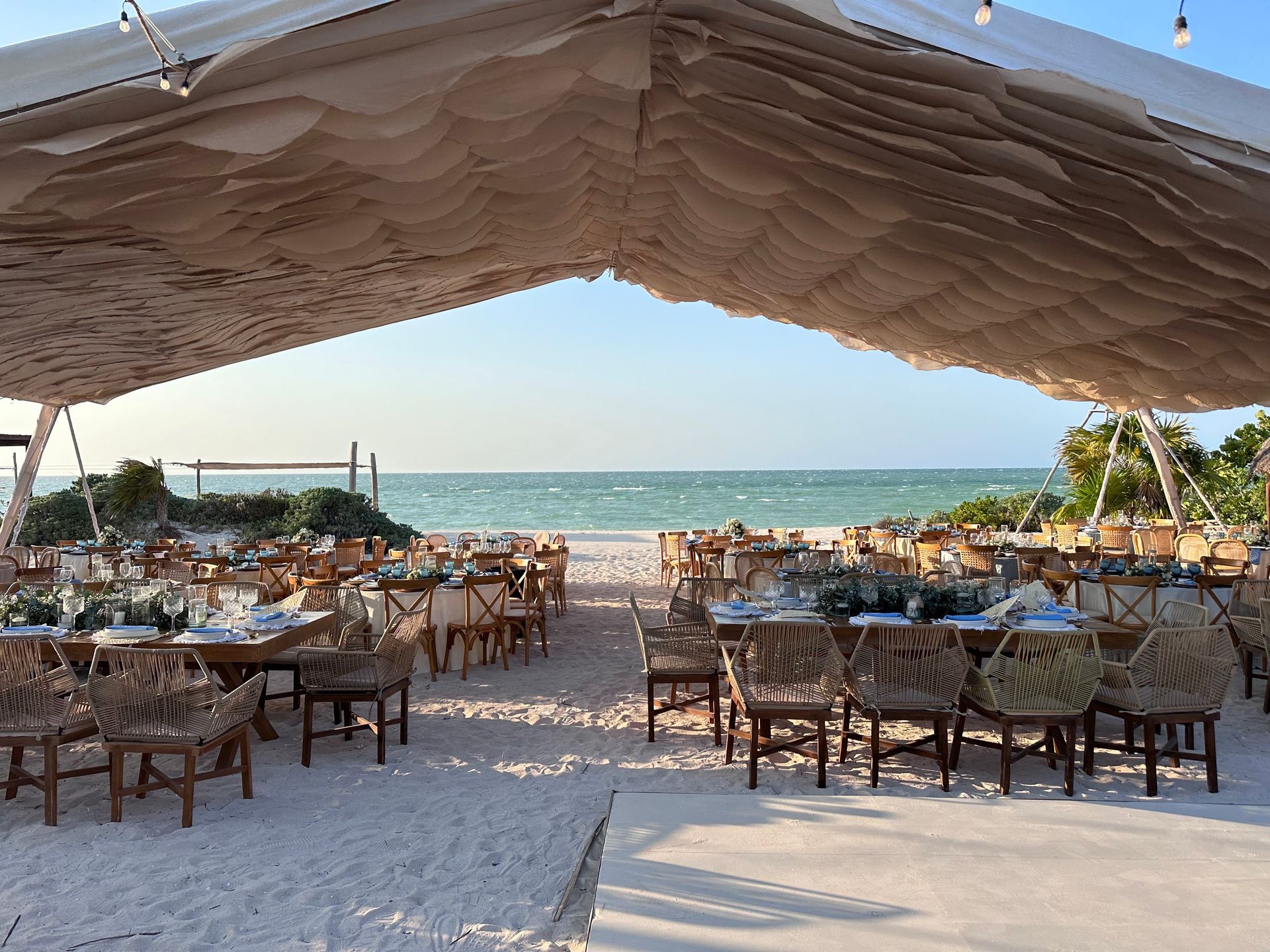 En la playa se instala una gran carpa con mesas y sillas.