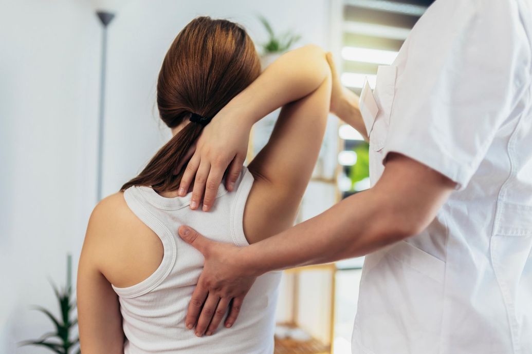 Person receiving a back massage from a practitioner in a bright clinic room
