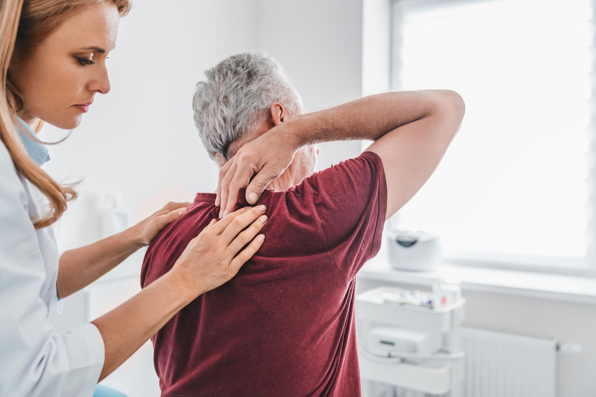 Therapist helping a patient stretch their shoulder in a bright clinic room