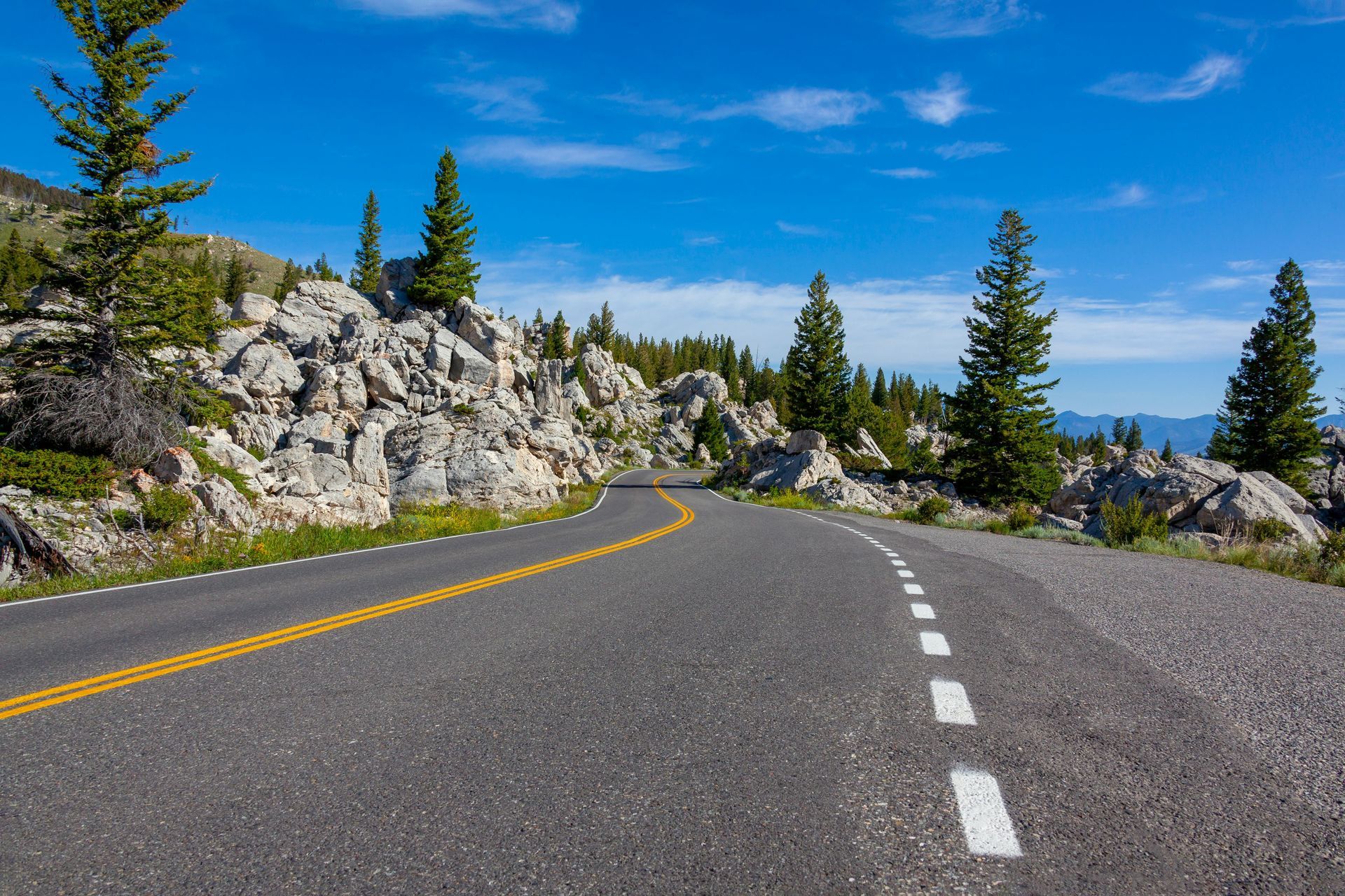 A road in the mountains with trees and rocks on both sides.