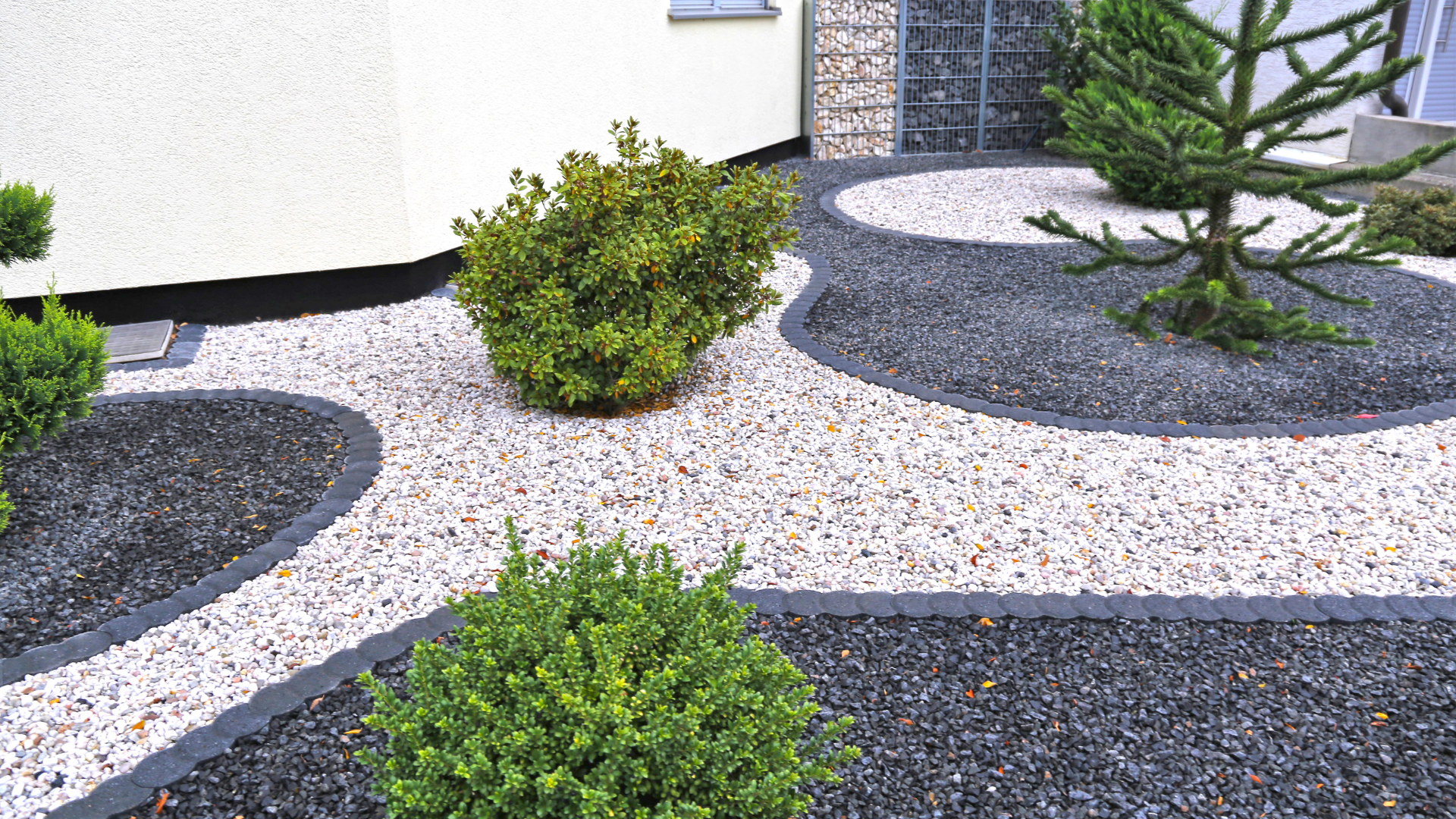 A garden with gravel and plants in front of a house.