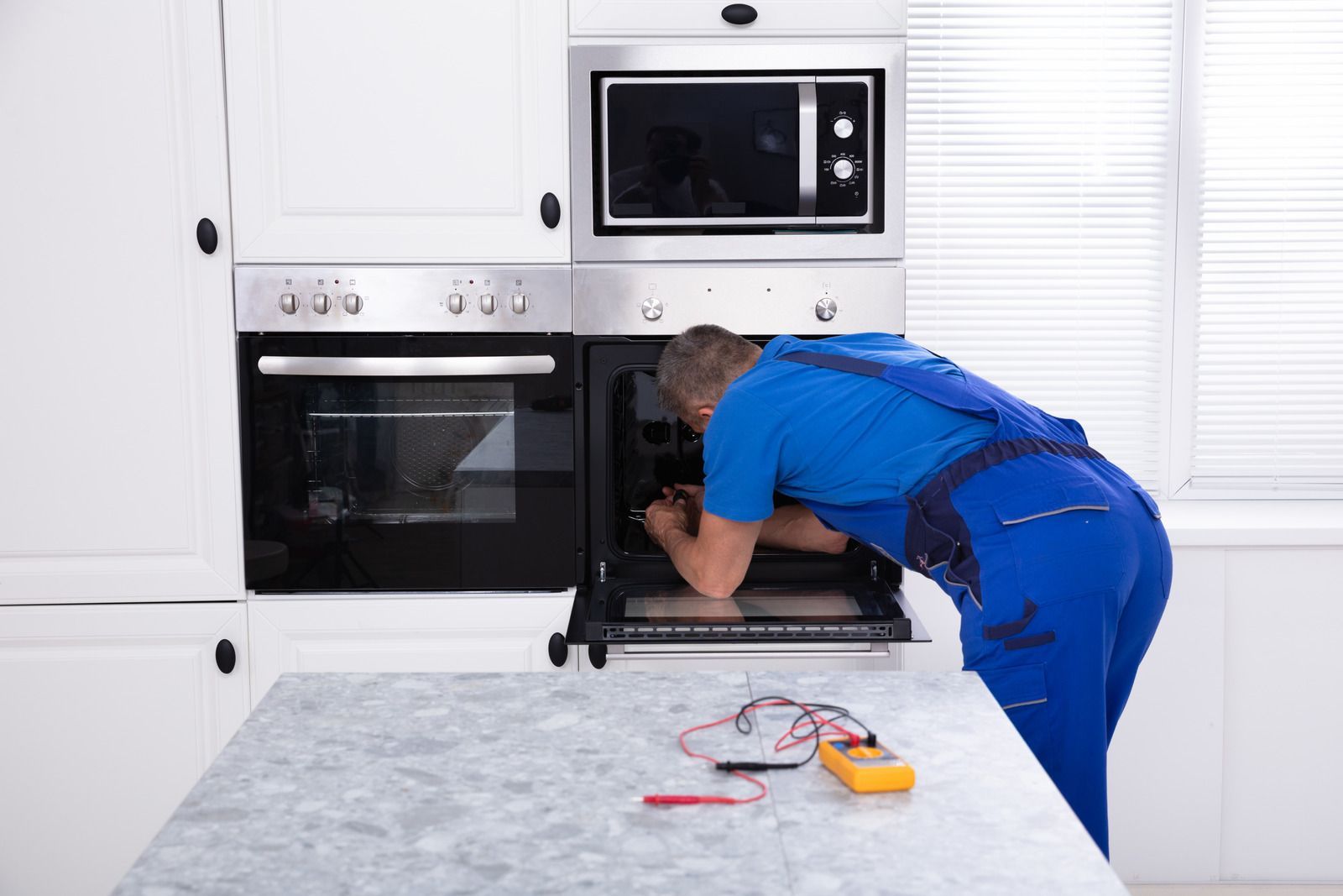 A man is working on an oven in a kitchen.