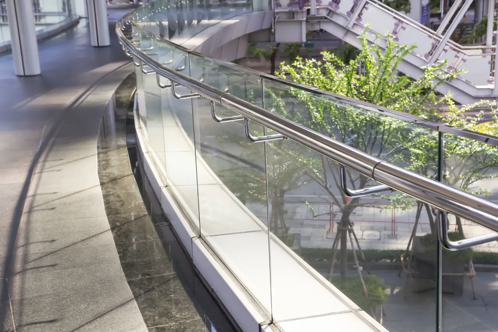 Curved indoor walkway with glass railings and sunlight filtering onto surrounding greenery — Channel Glazing In Electrona, TAS