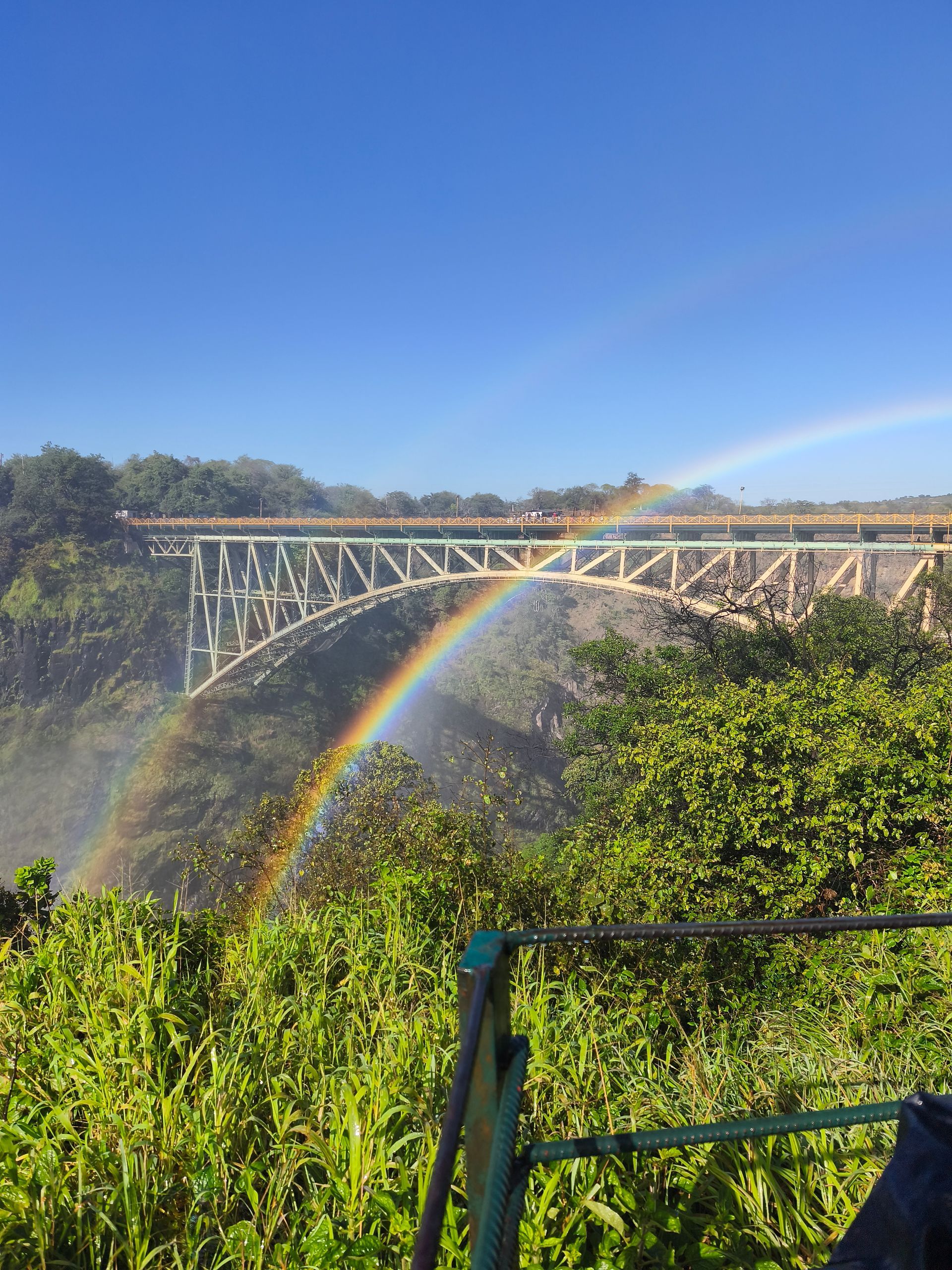 A bridge over a river with a rainbow in the background