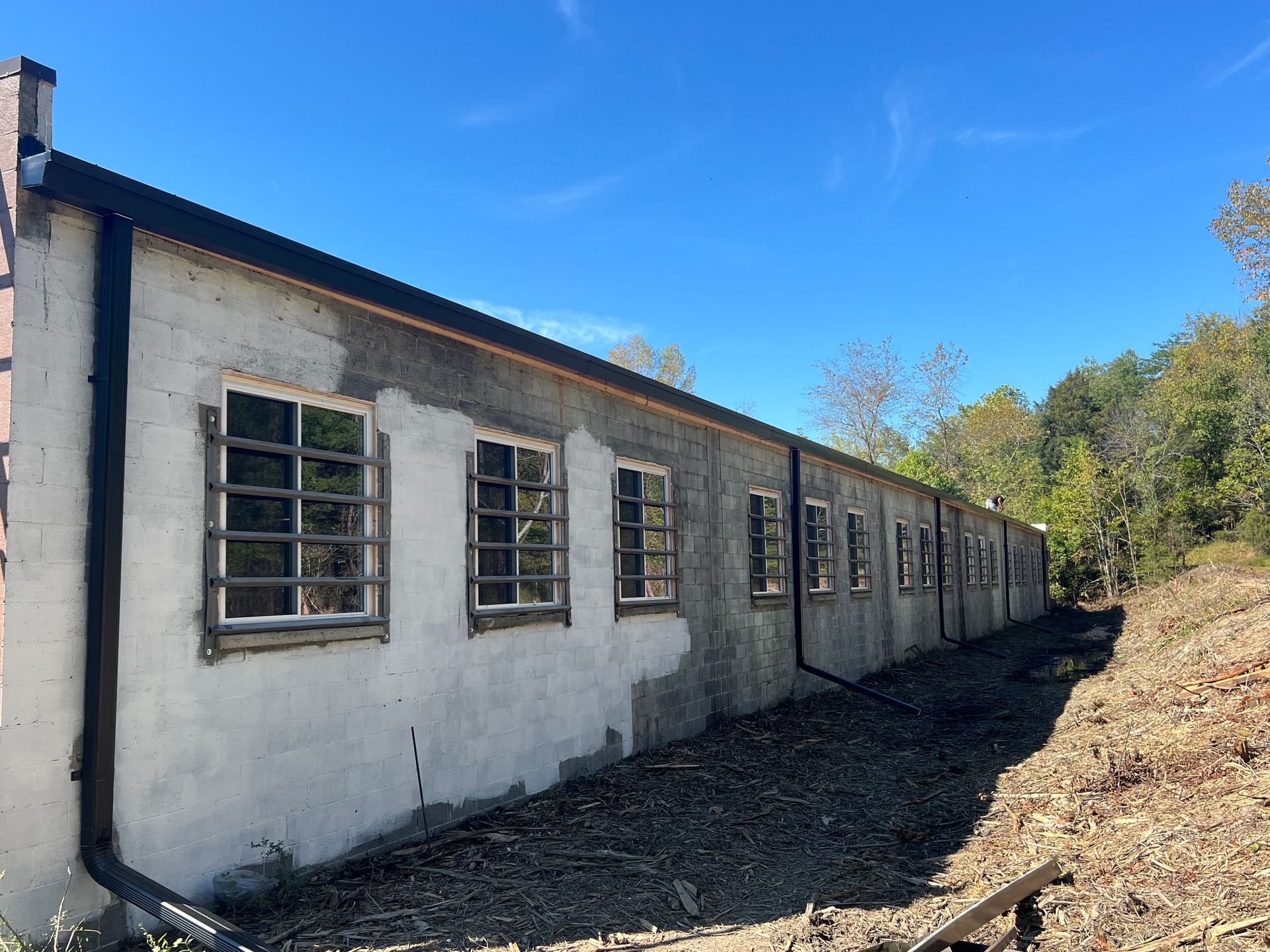 Long, one-story building with barred windows. Gray stucco exterior under blue sky.
