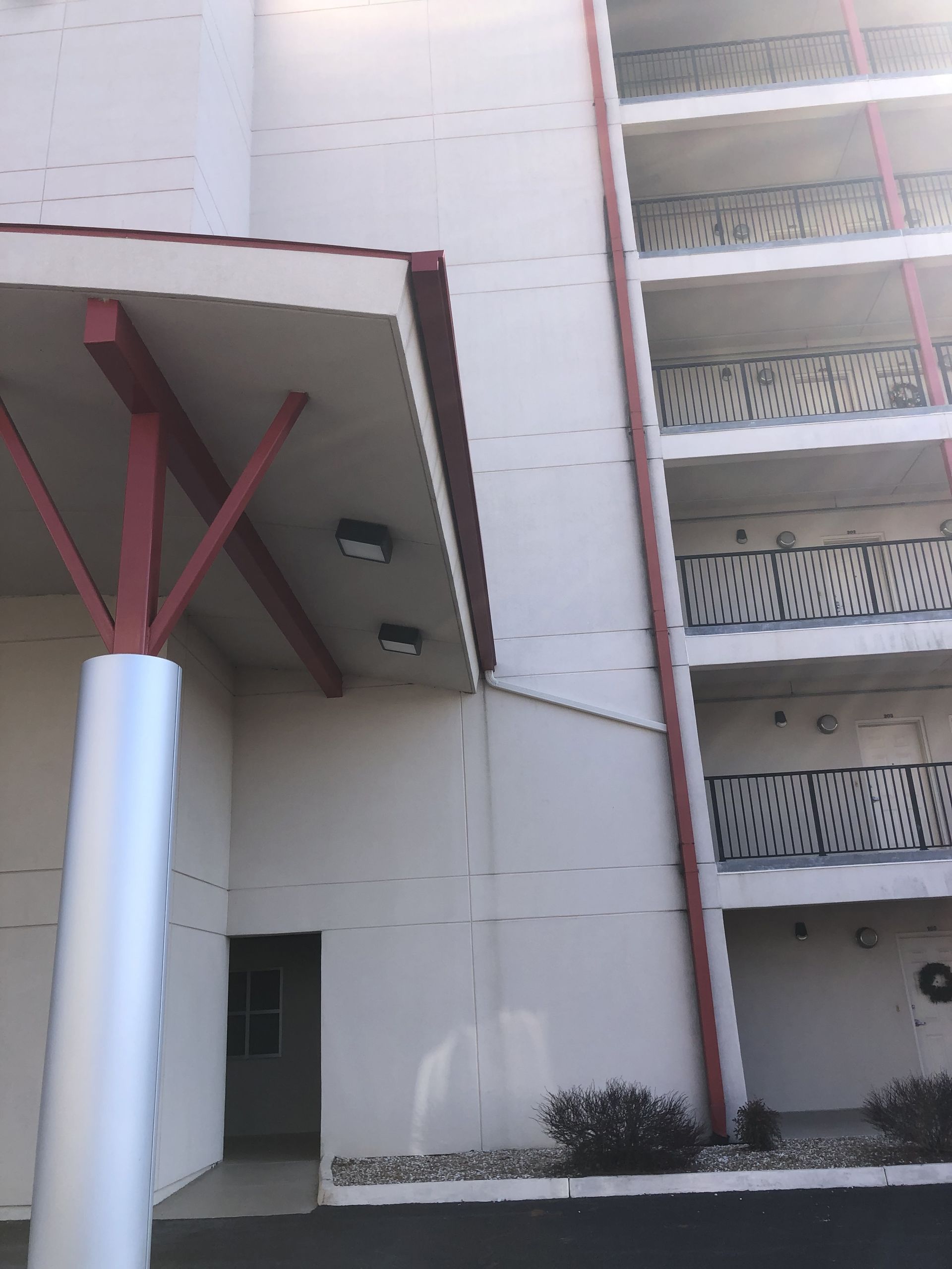 Exterior of white building with red accents and balconies.