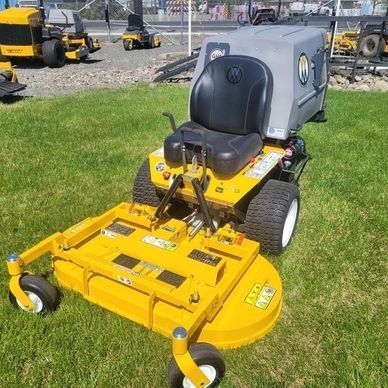 Yellow and gray riding lawnmower on green grass; outdoor setting