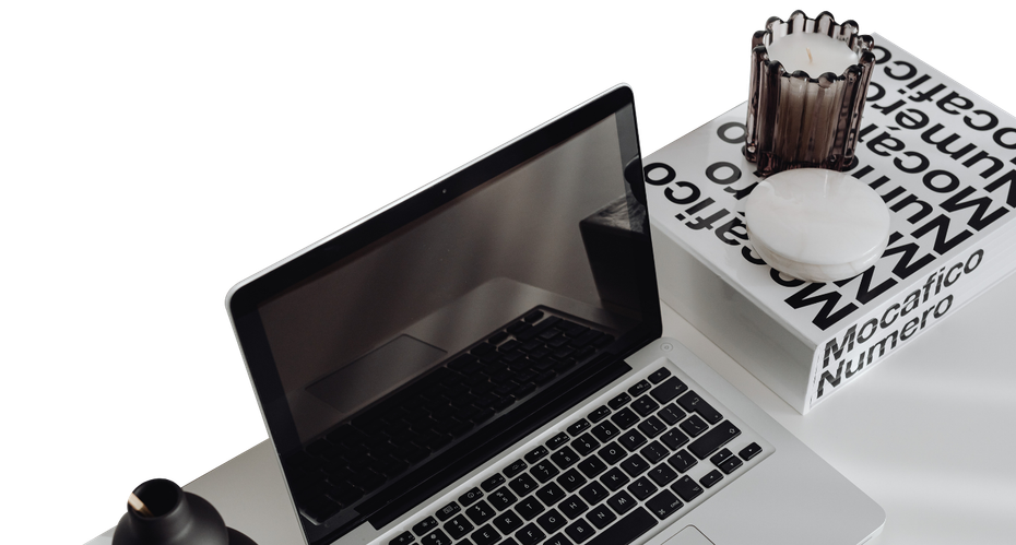 Laptop on white desk beside a pen cup and a block with a stylized gear graphic