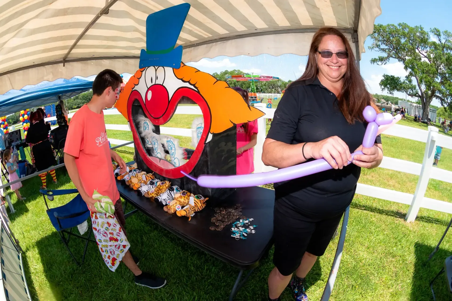 A woman is holding a balloon in front of a clown sculpture.