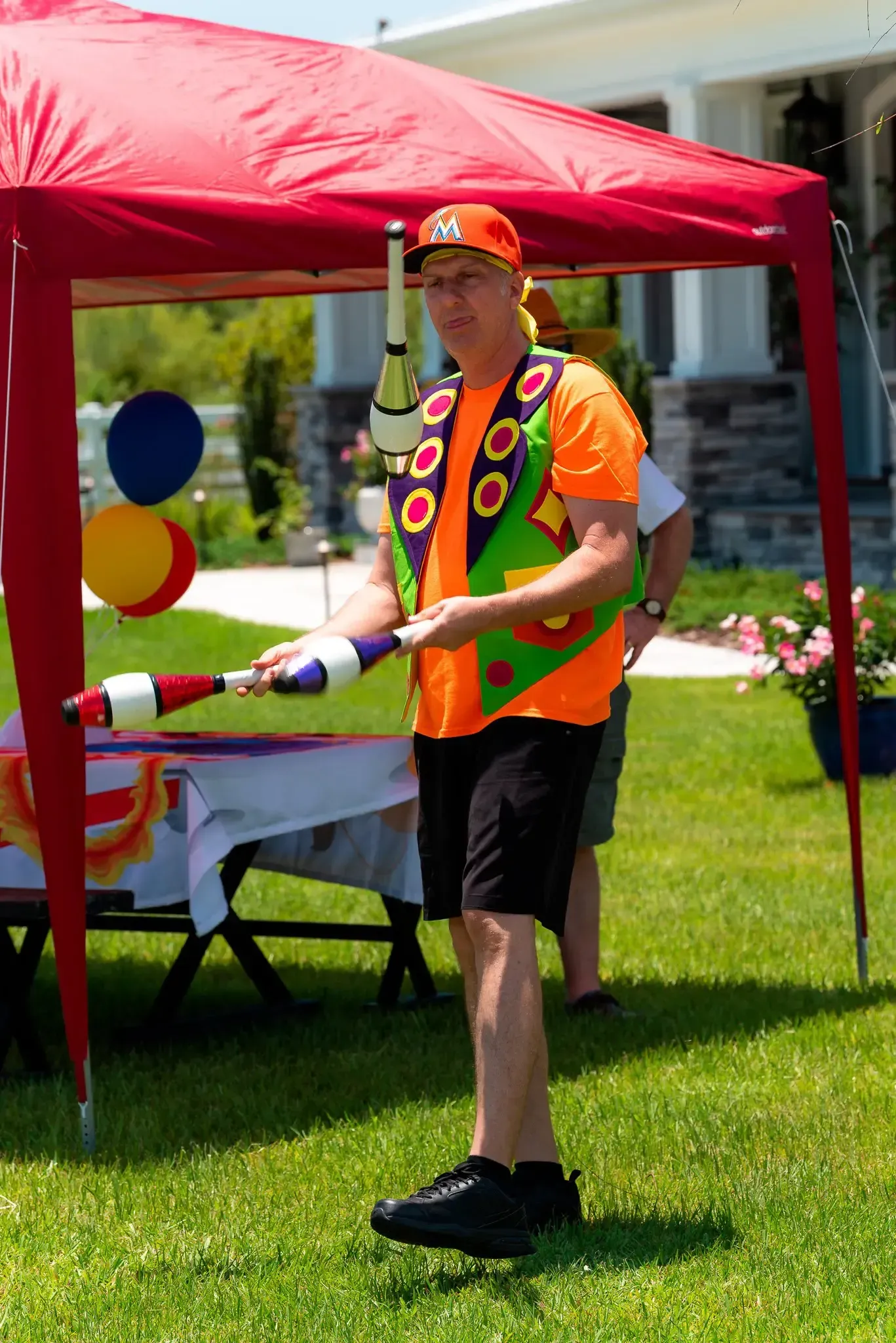 A man is juggling a ball in front of a red tent.