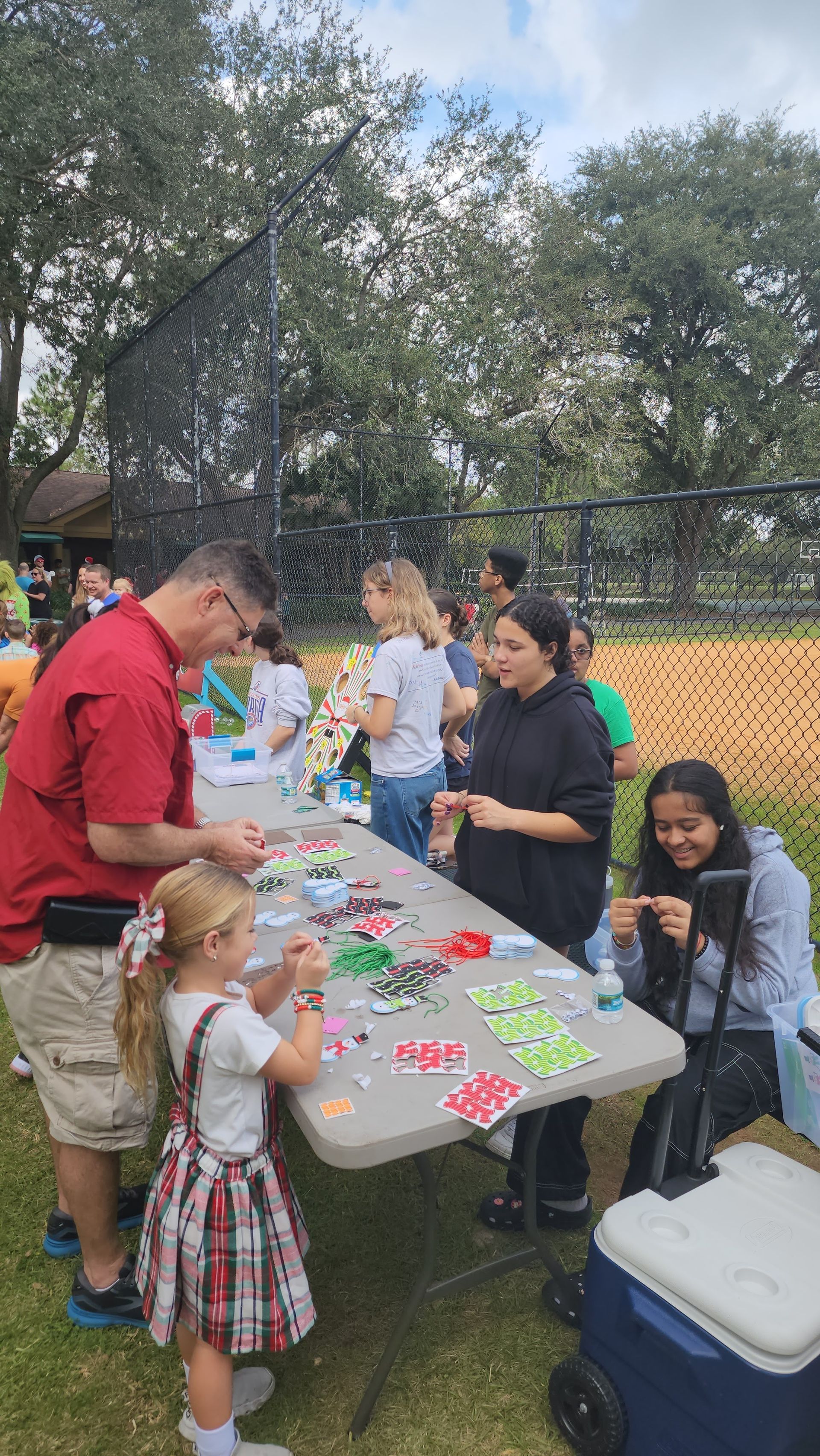 A group of people are sitting around a table in a park.