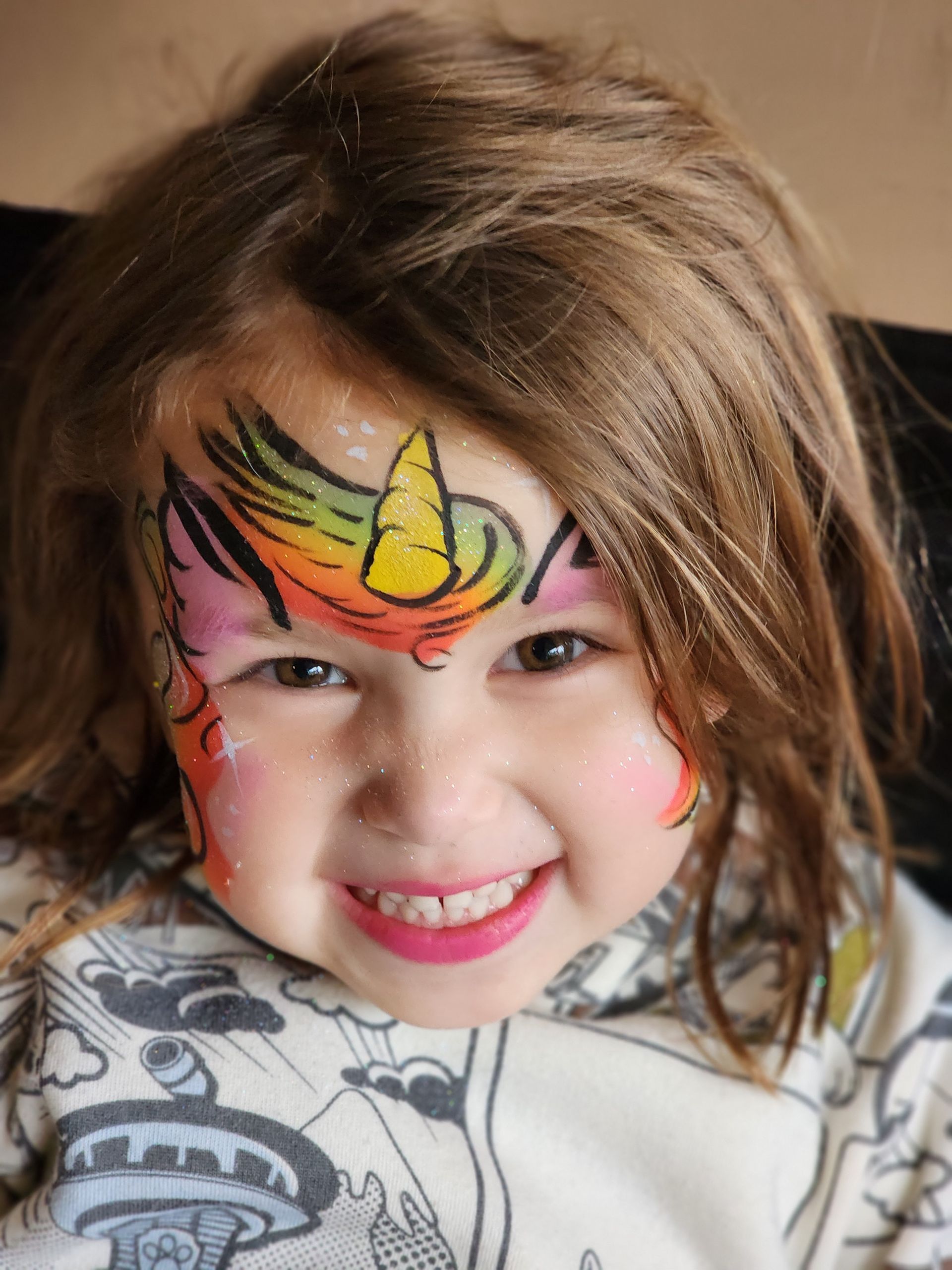 A little girl with her face painted like a unicorn.