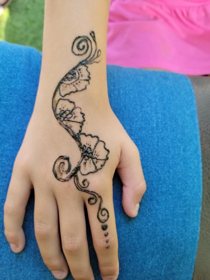 A woman 's hand has a tattoo of flowers and swirls on it