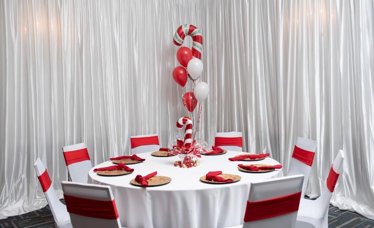 A round table with red and white chairs and a candy cane centerpiece.