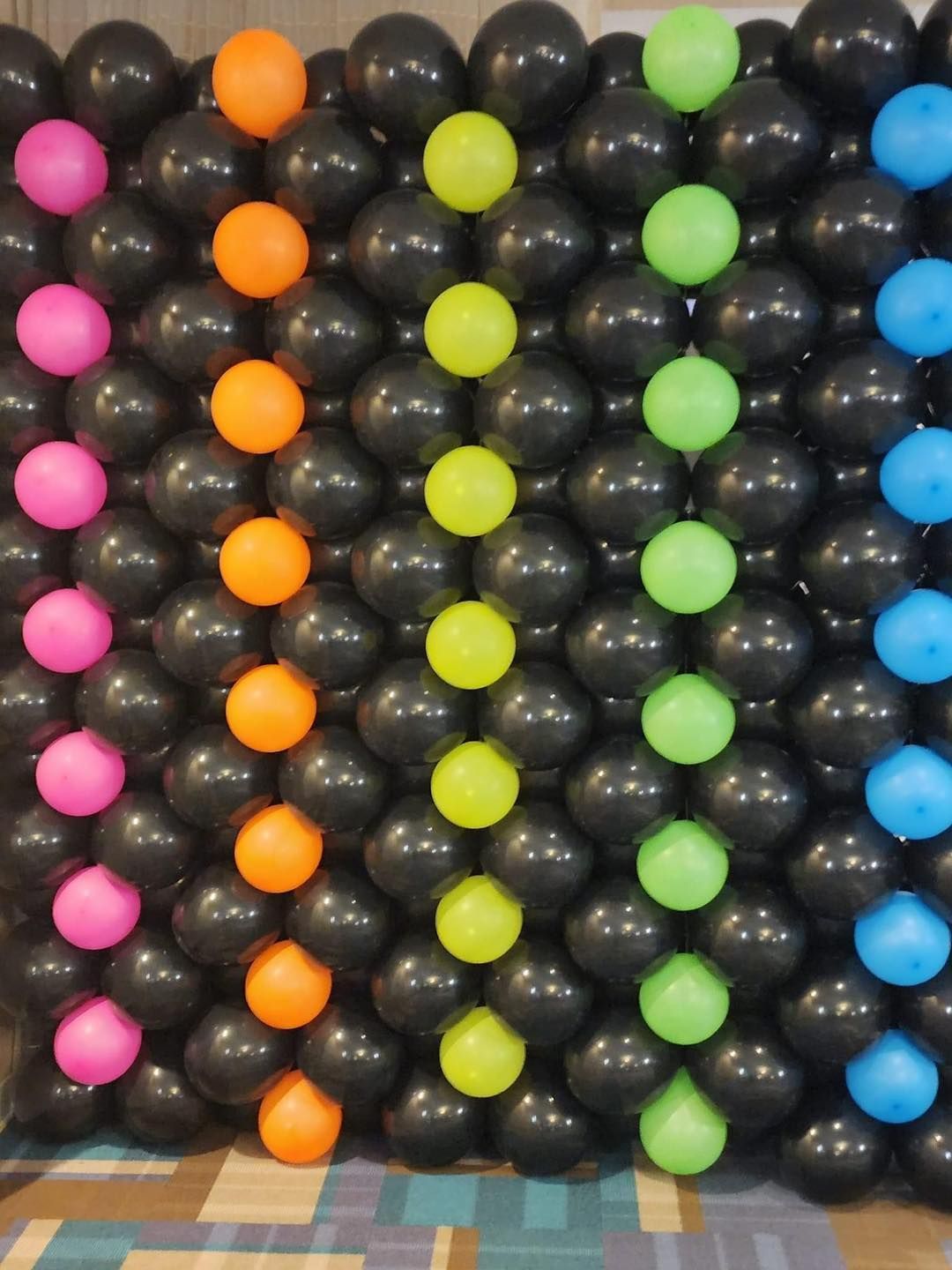 A wall of black and neon colored balloons