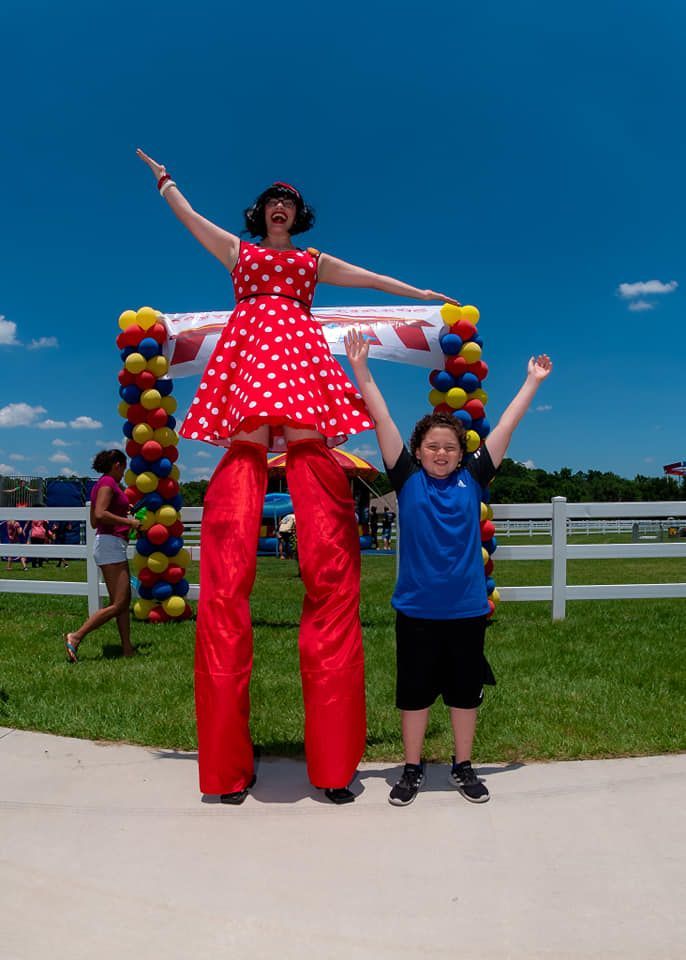 A woman on stilts is standing next to a boy in a blue shirt