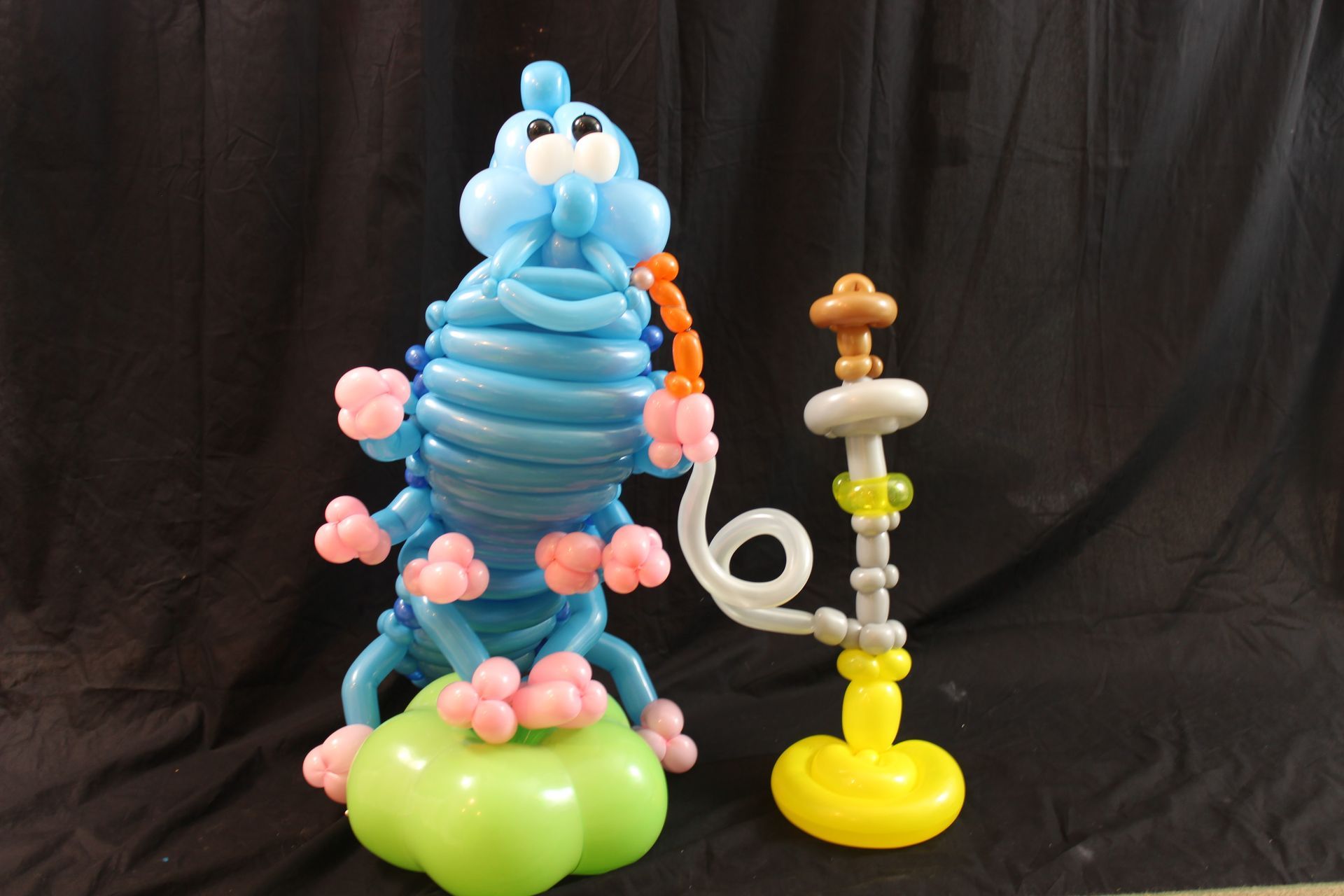 A blue caterpillar made out of balloons next to a hookah