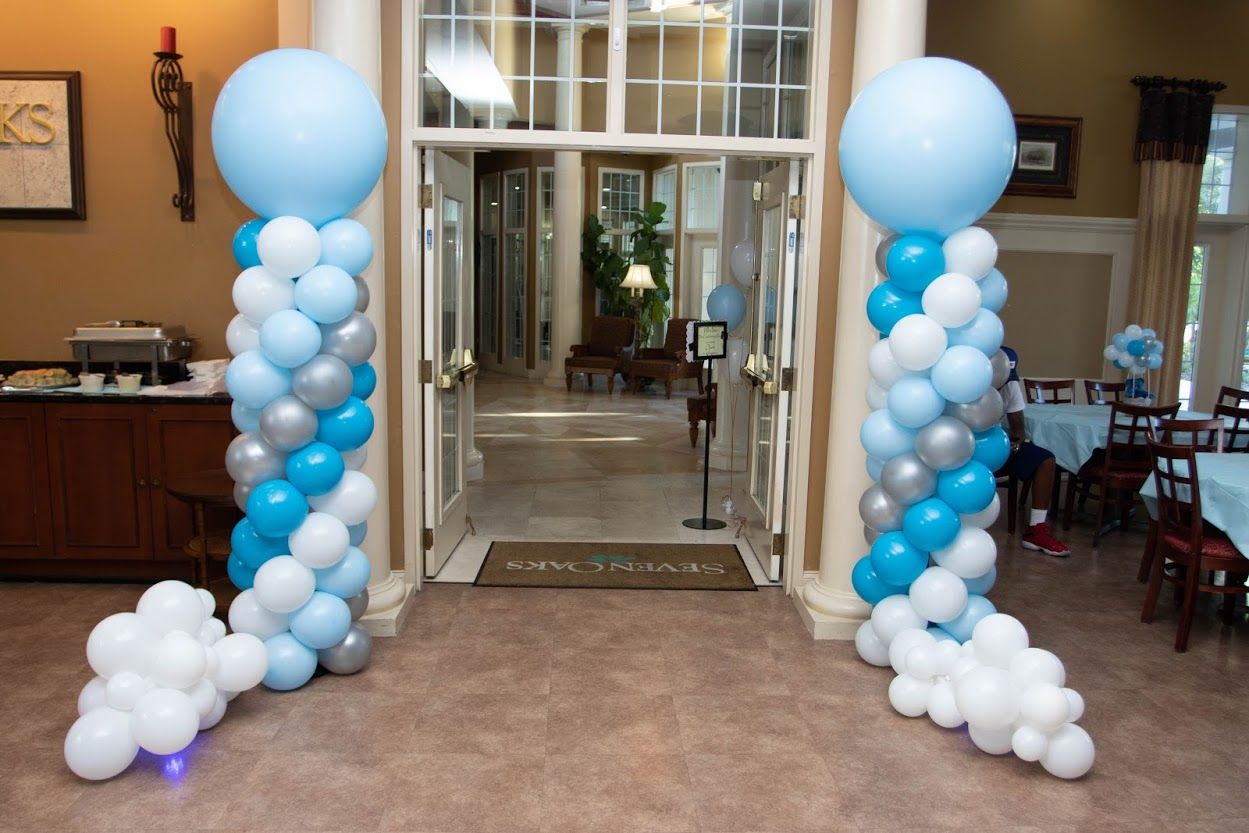 A room decorated with blue and white balloons and columns