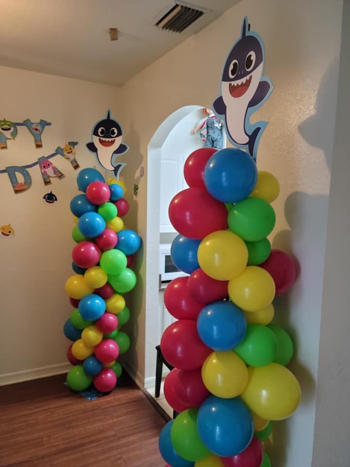 A room decorated with colorful balloons and a baby shark balloon.