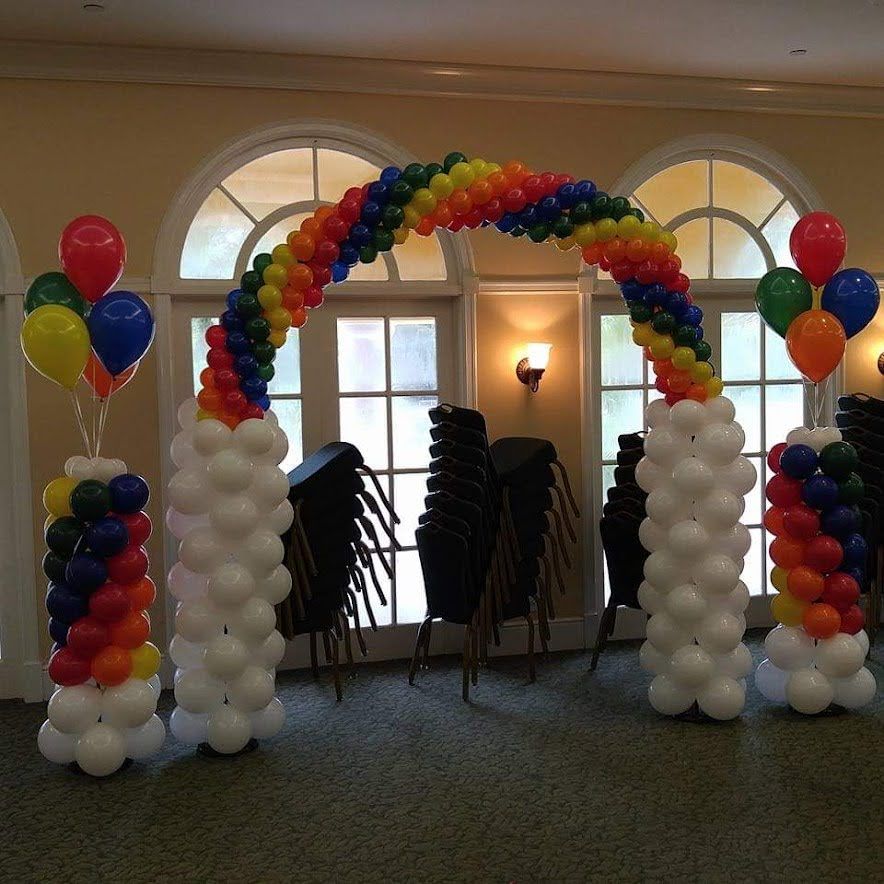 A room decorated with balloons including a rainbow arch