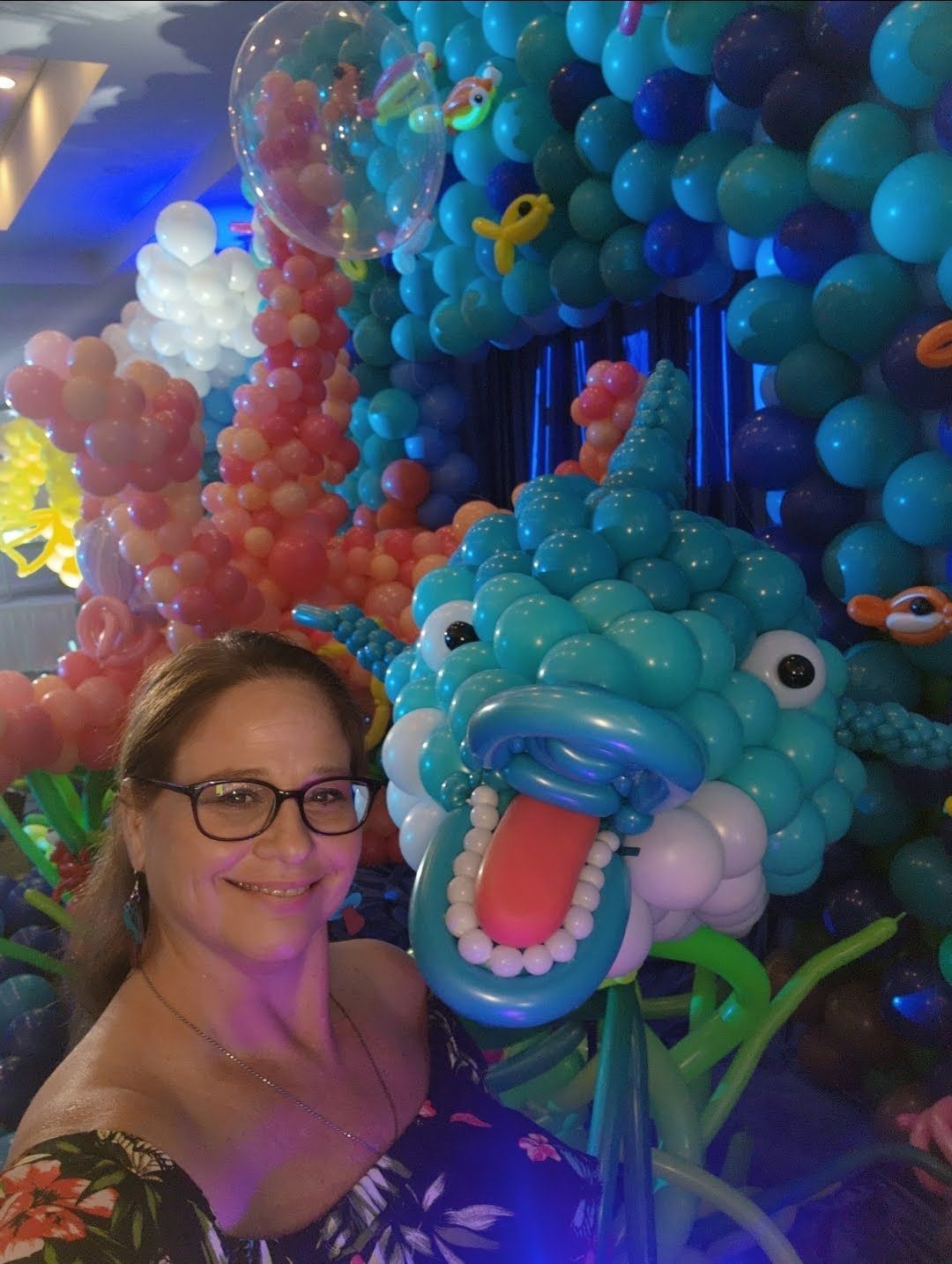 A woman is standing in front of a wall of balloons.