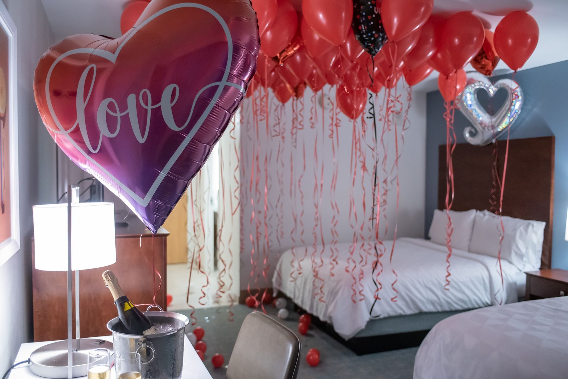 A hotel room decorated for valentine 's day with balloons and a heart shaped balloon.