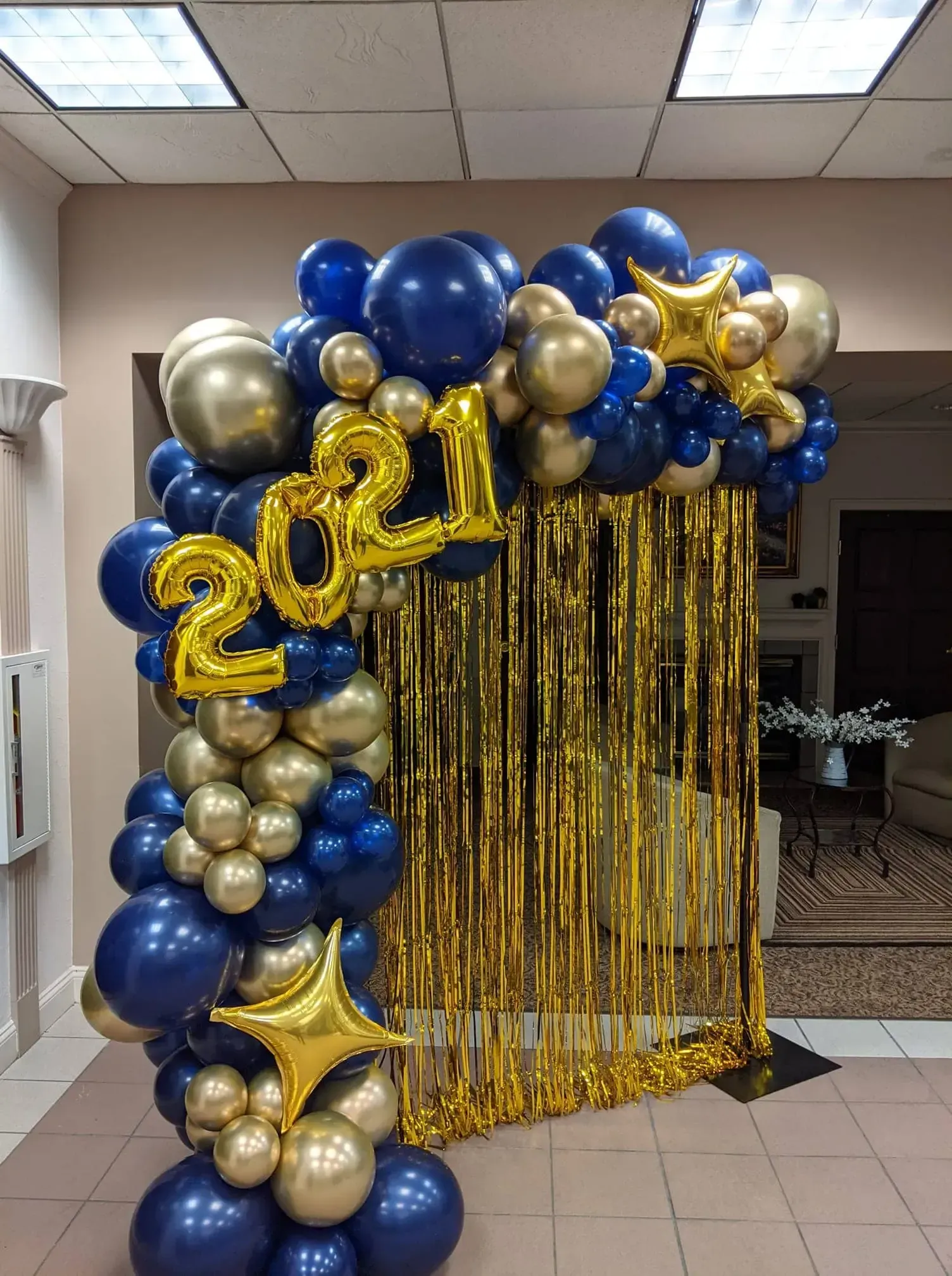 A room filled with blue and gold balloons and a gold curtain.