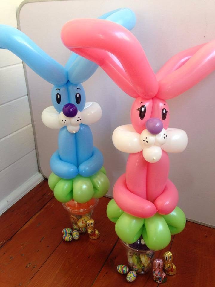Two bunnies made out of balloons are sitting next to each other on a wooden floor.