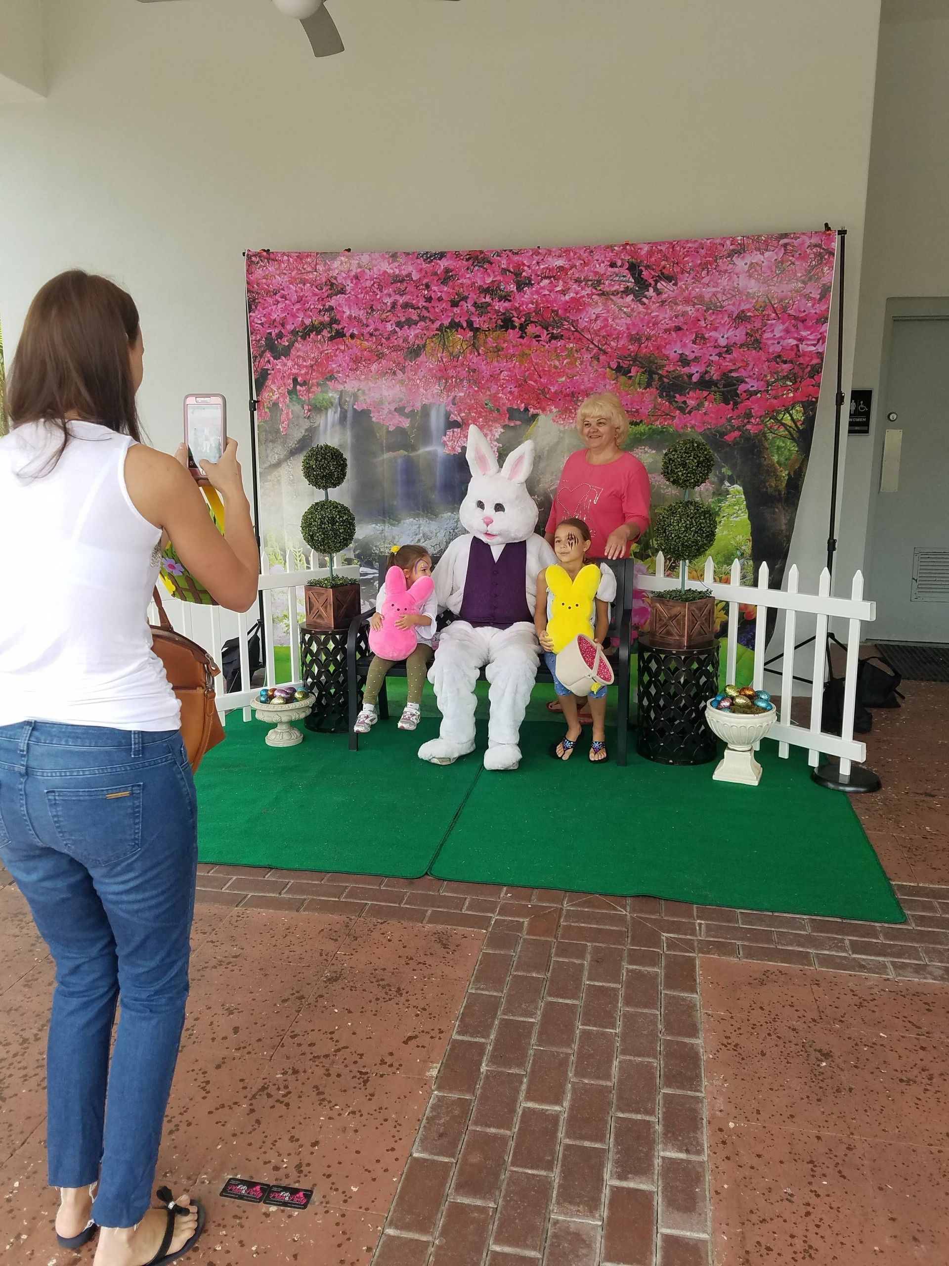 A woman is taking a picture of a bunny and two children.