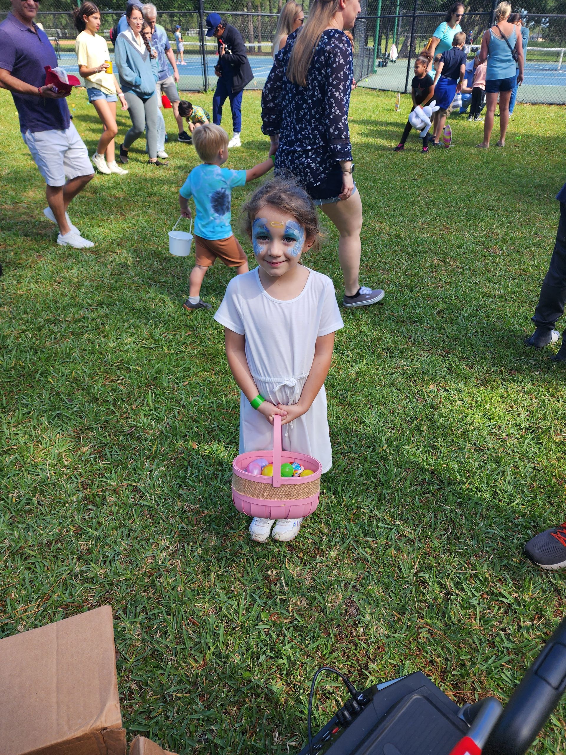 A group of young girls are sitting in the grass with some rabbits and eggs.