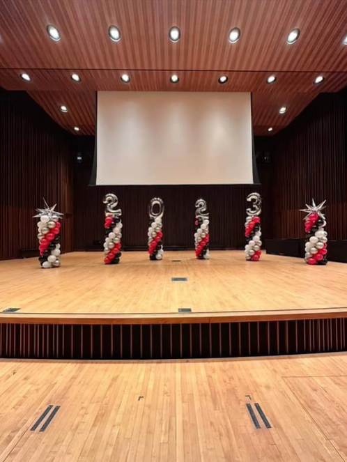 A stage with balloons on it and a large screen