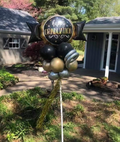 A bunch of balloons are sitting on a pole in front of a house.