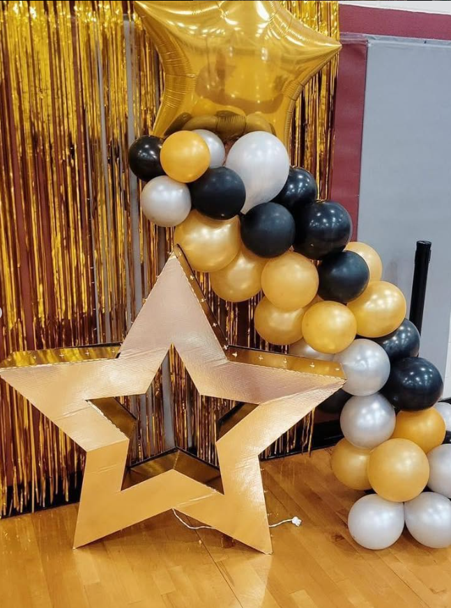A star made of balloons is sitting on a wooden floor.