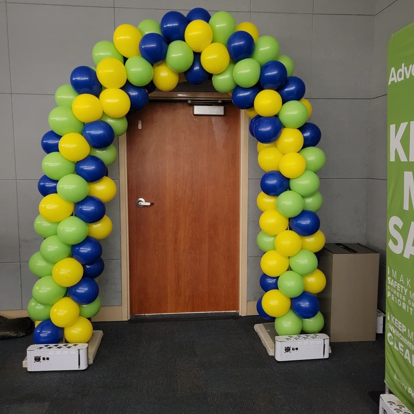 A green and yellow balloon arch is in front of a door