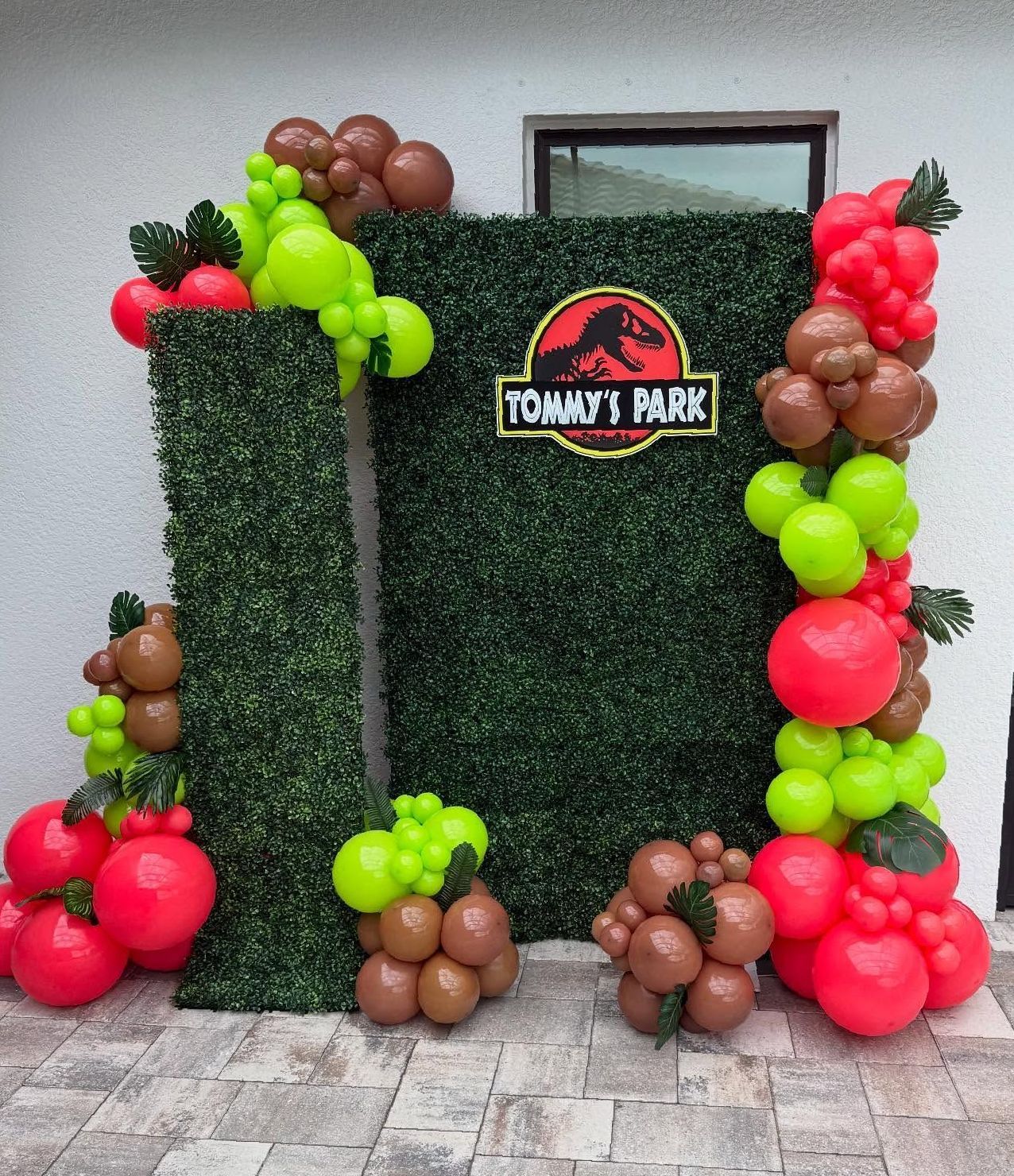 A wall decorated with balloons and a sign that says tommy 's park.