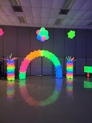 A room decorated with glow in the dark balloons and a glow in the dark arch.
