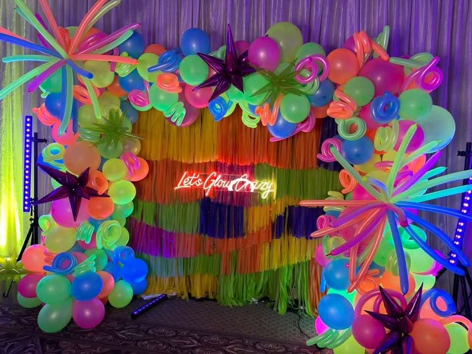 A room decorated with neon balloons and a neon sign.