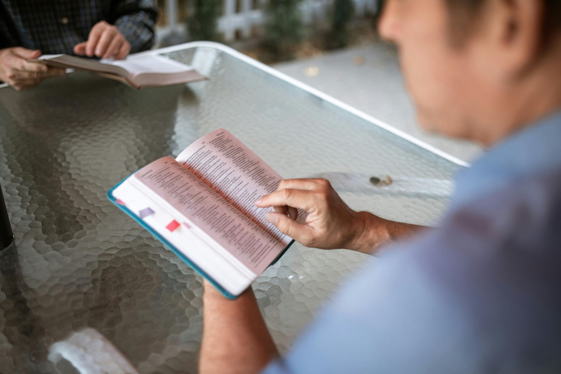 A man is reading a bible while sitting at a table.
