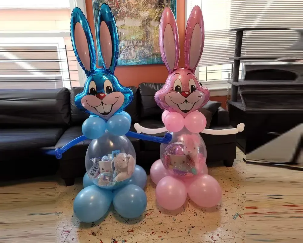 Two bunnies made out of balloons are standing next to each other in a living room.